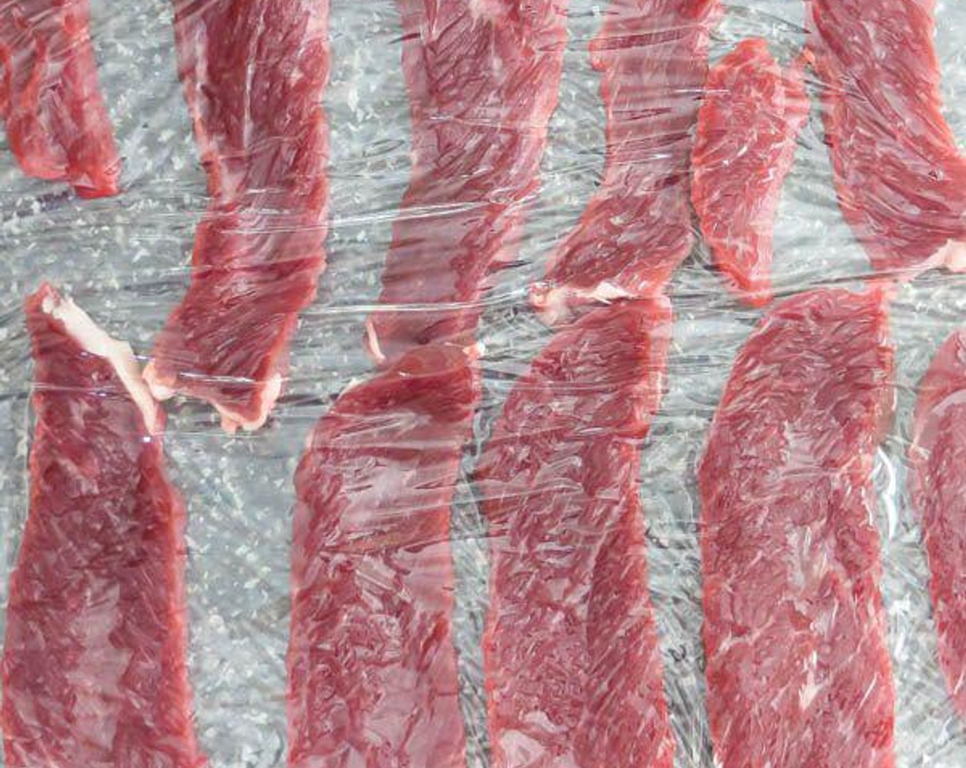 step 5 While the water simmers, prepare the Sirloin Steak (5 oz). Lay a large piece of plastic wrap over a cutting board. With a sharp knife, cut the beef into thin slices and lay them on the plastic wrap.