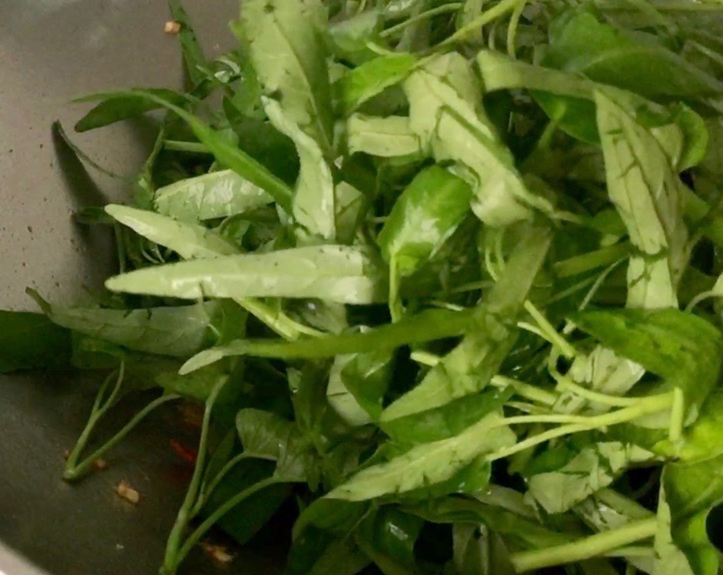 step 9 Add in the drained chinese water spinach. Using a folding motion, stir fry the greens briefly for 30 seconds. Stir fry until the leaves have just withered and vegetable is moist.