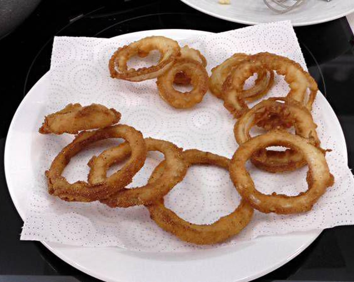 step 7 As the rings are finish frying, remove them from the frying pan and place them on a plate with paper towels to absorb the excess oil.
