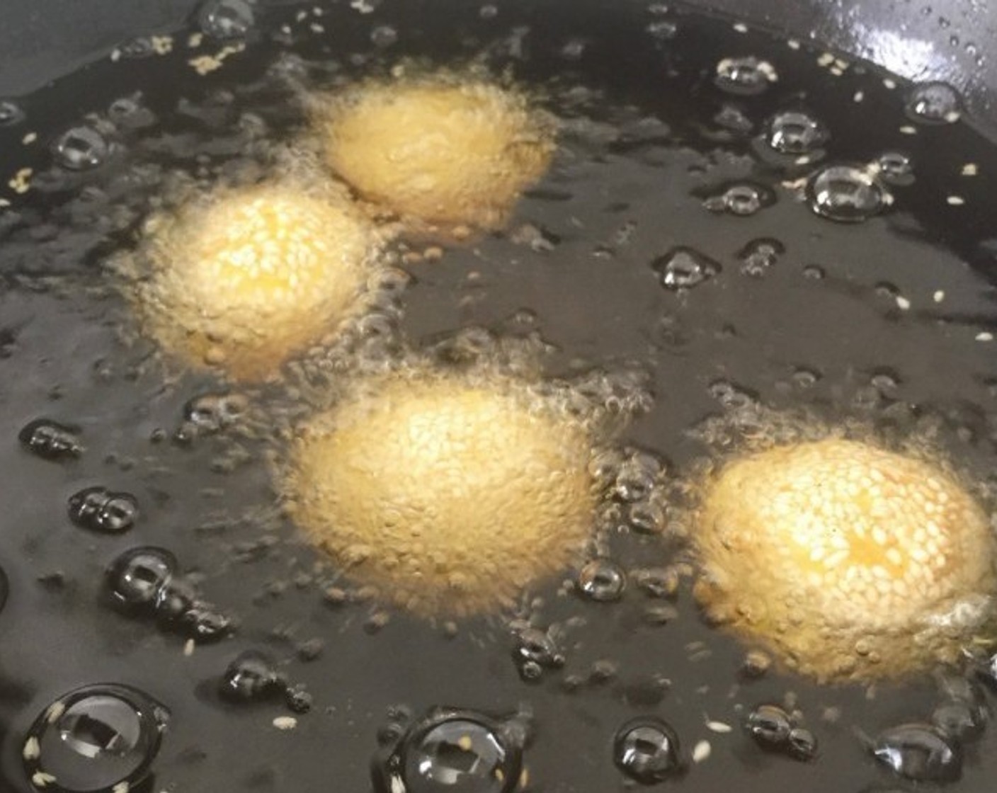 step 16 In batches, add in the sesame cookie balls into the hot oil. Then bring the temperature to medium low and fry the dough for about 10 minutes or until the balls crack and are about golden brown in colour.