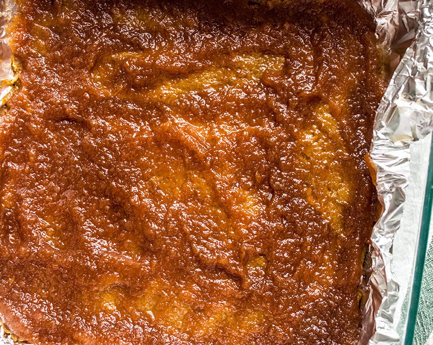 step 6 Press half of the dough mixture into the bottom of the lined 8x8 pan then spread Apple Butter (1/3 cup) over the bottom dough. You want a thin layer to cover all of the first layers, this should take approximately 1/2 cup, but you may not need quite that much.