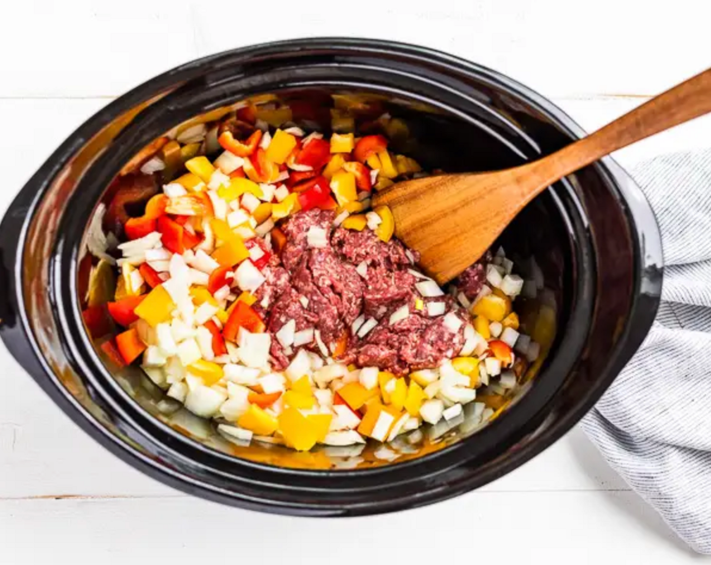 step 1 Place the Onion (1), Red Bell Peppers (2), and Ground Beef (1 lb) into the slow cooker bowl. Use a wooden spoon to break up the meat into small pieces.