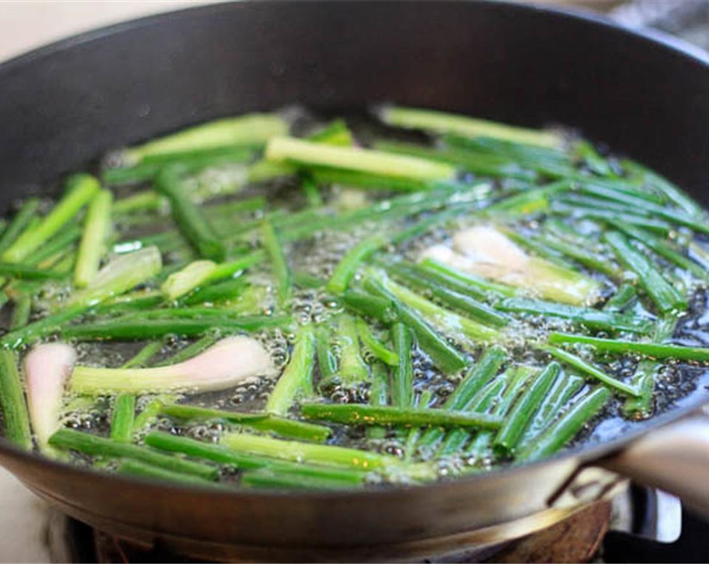 step 1 Wash the Scallions (2 bunches) and cut into 5 cm long segments. Pat dry. Heat Cooking Oil (1 cup) and put the green onion pieces in. Use a low heat. Simmer until the green onions are deep-browned and almost burnt. Transfer into a bowl to cool down.