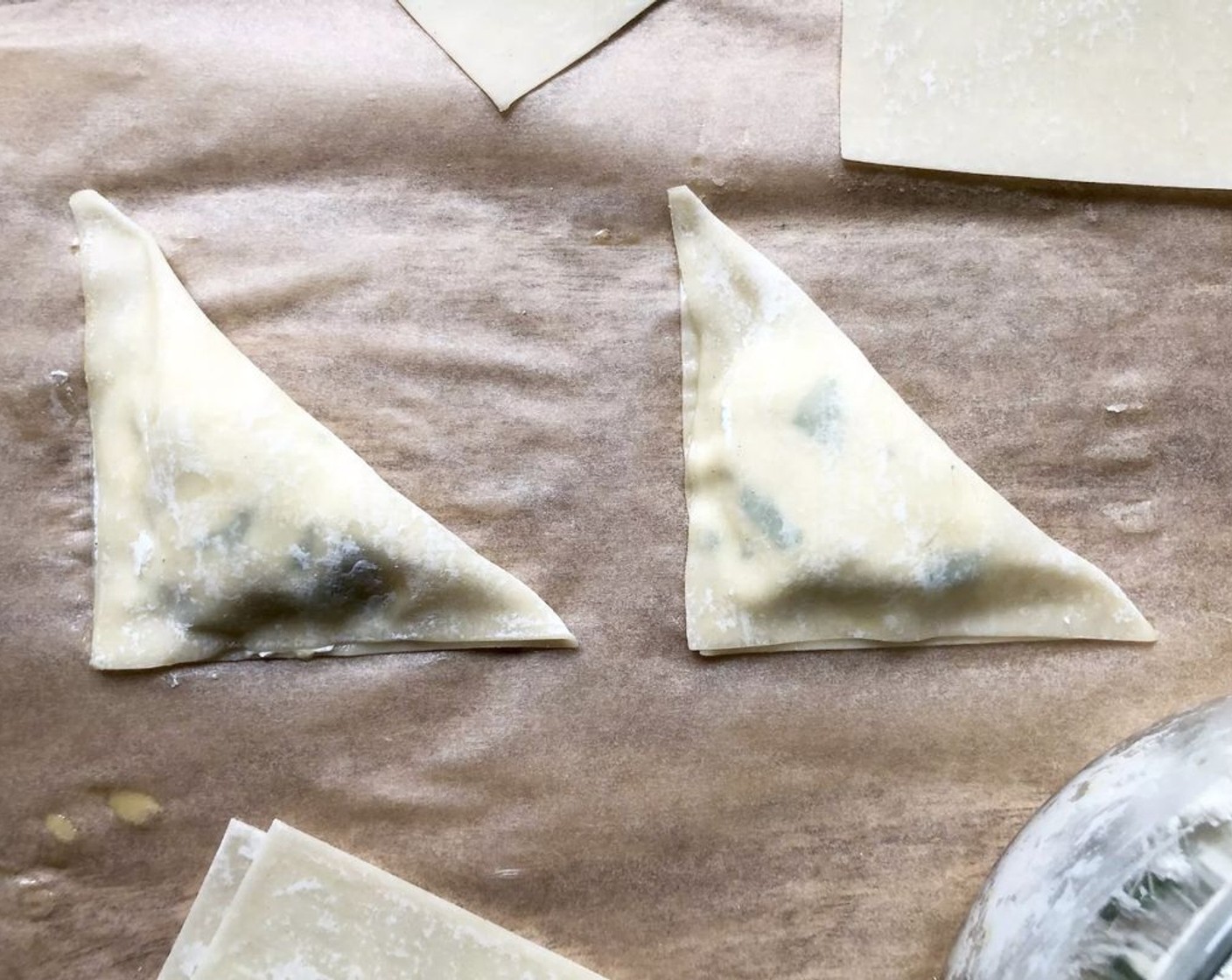 step 3 Fold each wrapper in half, forming a triangle, pressing well to seal the edges. Cover with a damp towel to prevent drying. Repeat the procedure with the remaining Wonton Wrappers (8), beaten egg, and ricotta mixture.