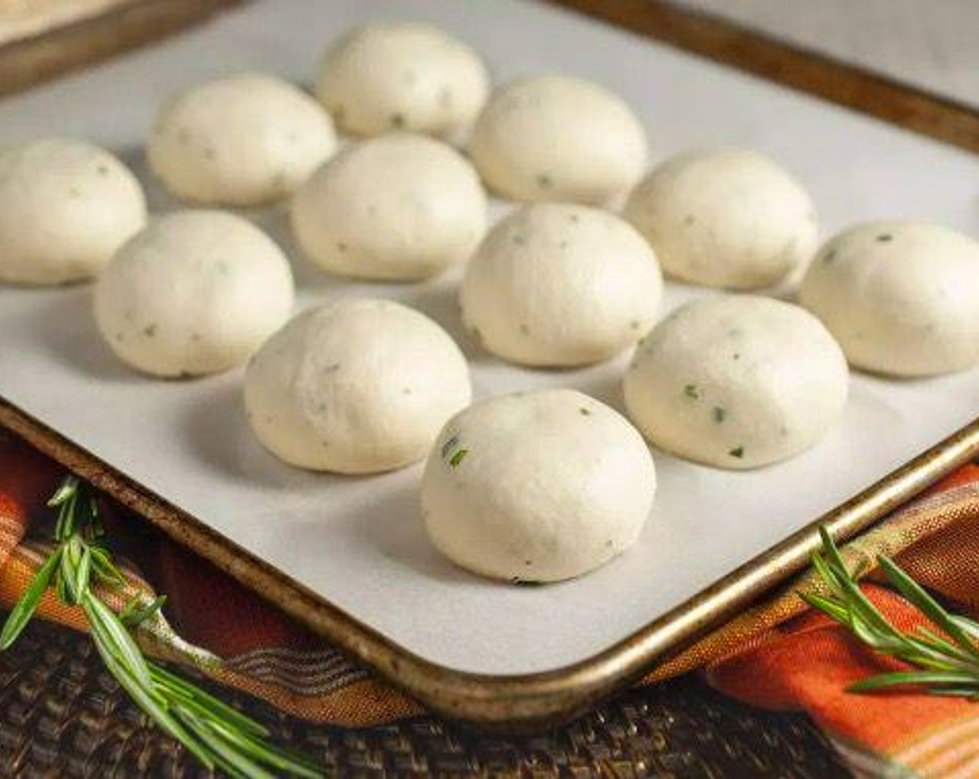 step 8 Divide dough into 12 equal portions of 55-58 grams each. Roll into balls and place on a parchment lined baking tray 1/4-inch apart. Cover with oiled plastic wrap or kitchen towel and allow to rise for 45 minutes.