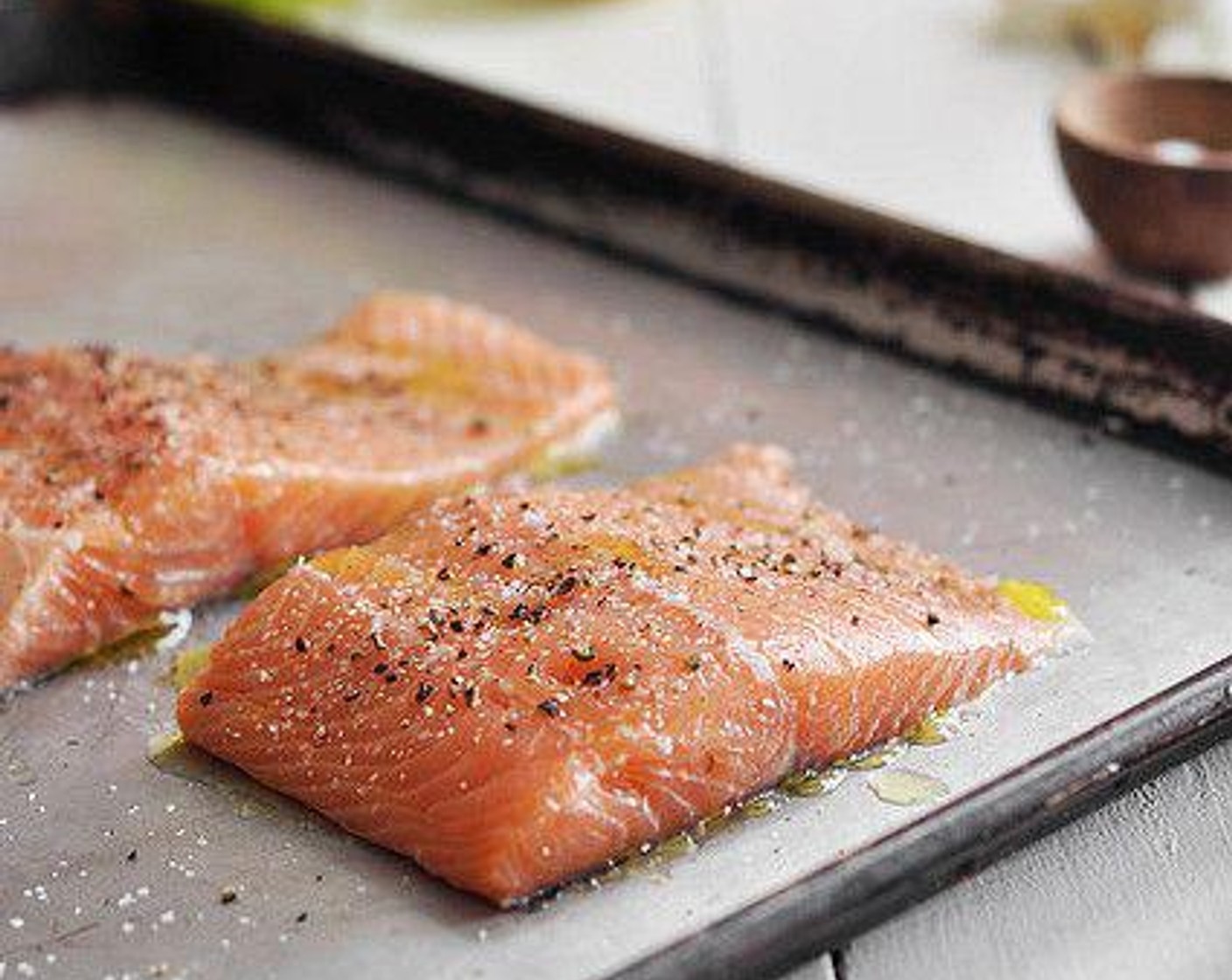 step 2 Place the Salmon (1 lb) skin side down onto a baking sheet. Drizzle each with Olive Oil (as needed), about a teaspoon on each. Season with Salt (1 tsp) and Freshly Ground Black Pepper (1 tsp)