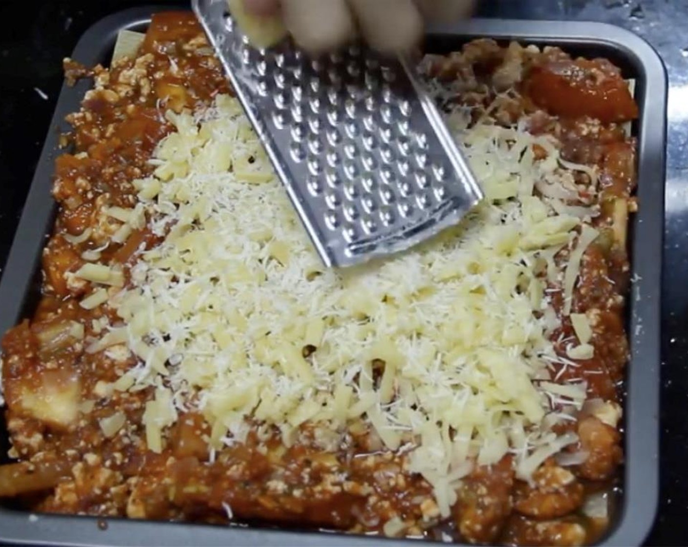 step 23 Add the rest of the tomato sauce and sprinkle another ¼ cup of shredded mozzarella, ¼ cup of shredded cheddar, and grate a generous amount of parmesan.