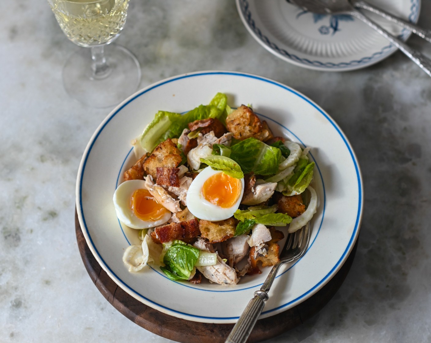 step 11 Tear the bacon into bite-sized pieces and scatter over the salad, followed by the croutons and chopped chicken. Sprinkle over the Parmesan Cheese (1/2 cup) and the anchovy dressing and use two spoons to lightly combine the ingredients. Plate the salad into individual bowls and top each with half a jammy egg.