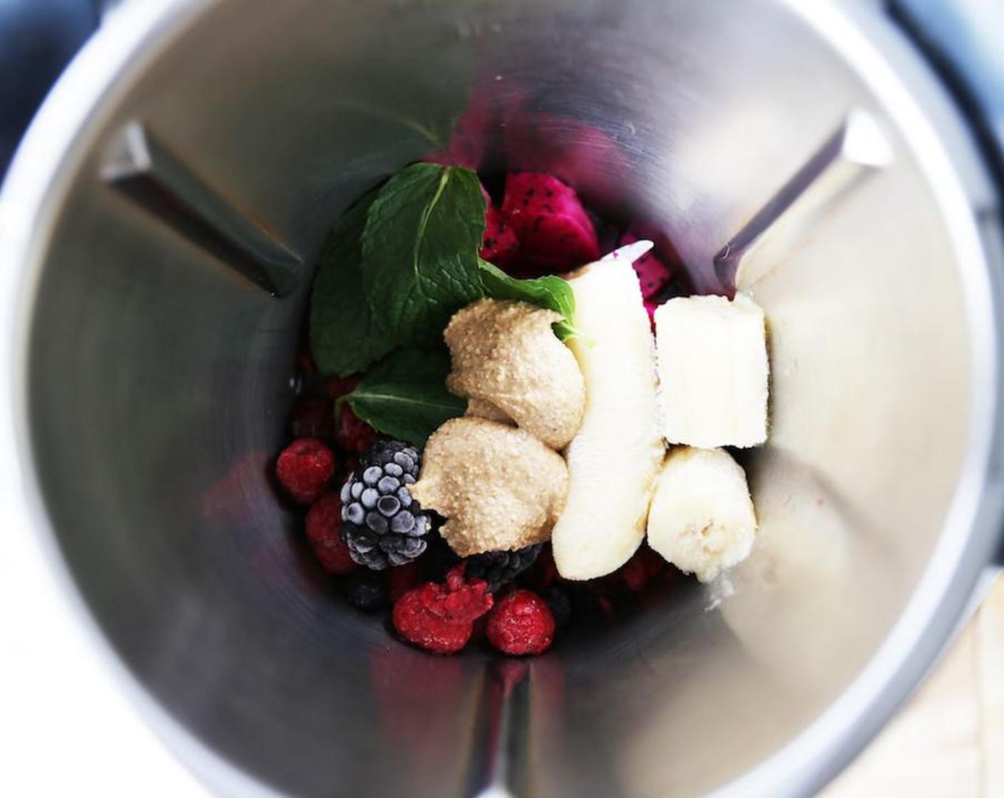 step 3 Add the Frozen Mixed Berries (1/2 cup), Dragon Fruit (3/4 cup), Banana (1 cup), Almond Butter (1 1/2 Tbsp), Coconut Chips (to taste), Fresh Mint Leaves (4), and Water (2 oz) into the blender and blend for 1 minute on Speed 7.