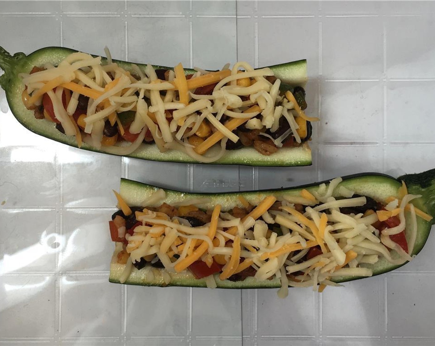 step 7 Stir this mixture well and check the seasoning. Add extra spices to taste if necessary. Fill the zucchini with this mixture and sprinkle with the Cheddar Cheese (4 Tbsp).