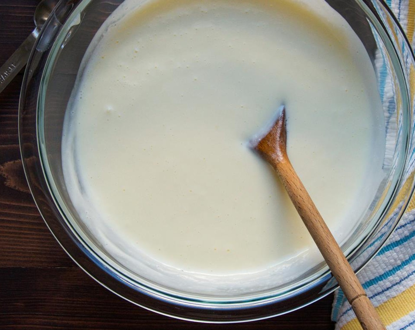 step 4 While the mixer is running, very slowly stream the hot cream into the egg mixture. Pour the egg mixture back into the saucepan and heat over medium heat, stirring constantly until the mixture thickens. Don't let it come to a boil, or the eggs will scramble.