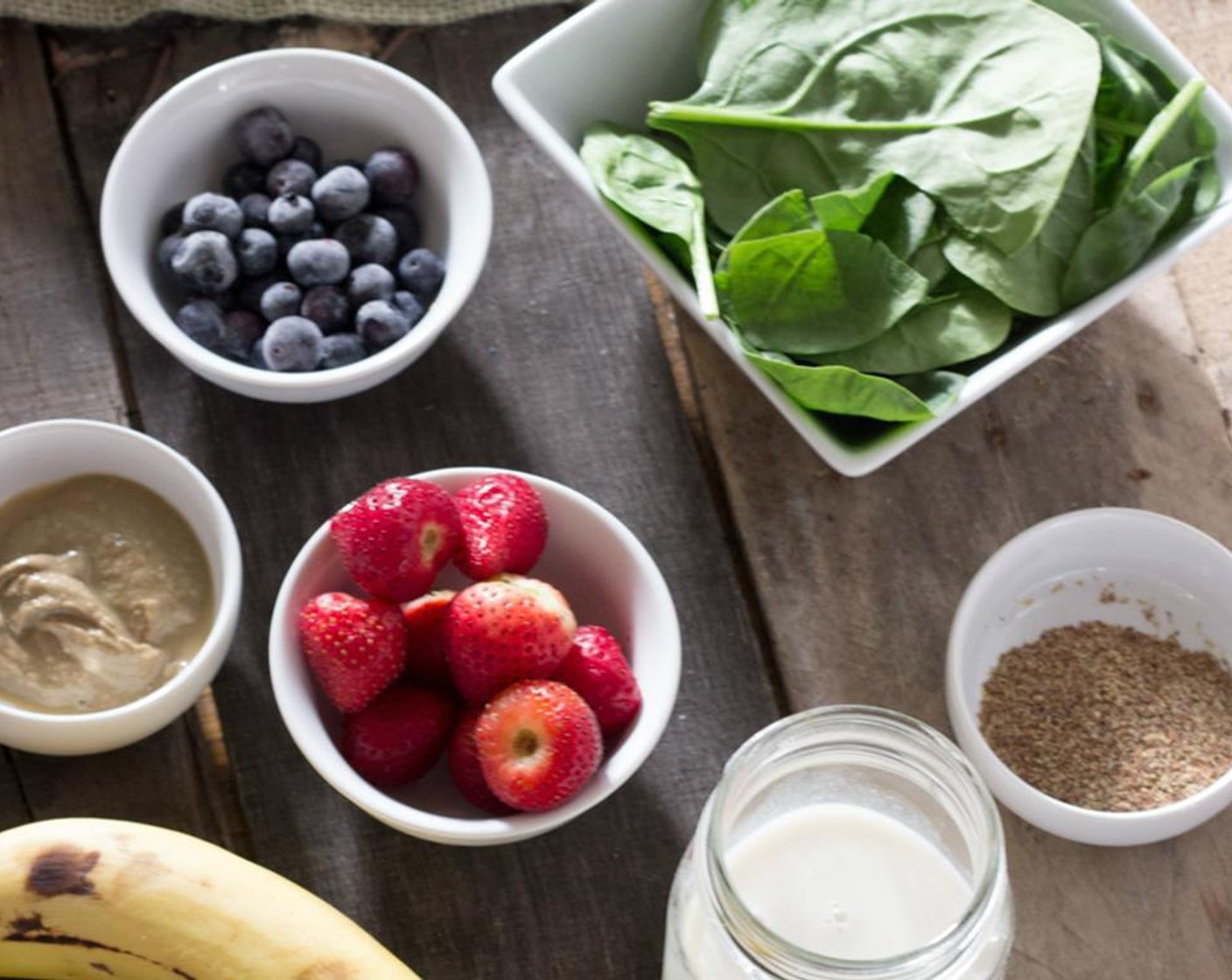 step 2 Add in Banana (1), Fresh Strawberry (1 cup), Frozen Blueberries (1/2 cup), Sunflower Seed Butter (1 Tbsp), Flaxseed Meal (1 Tbsp), Fresh Baby Spinach (2 cups), and Ice (to taste).