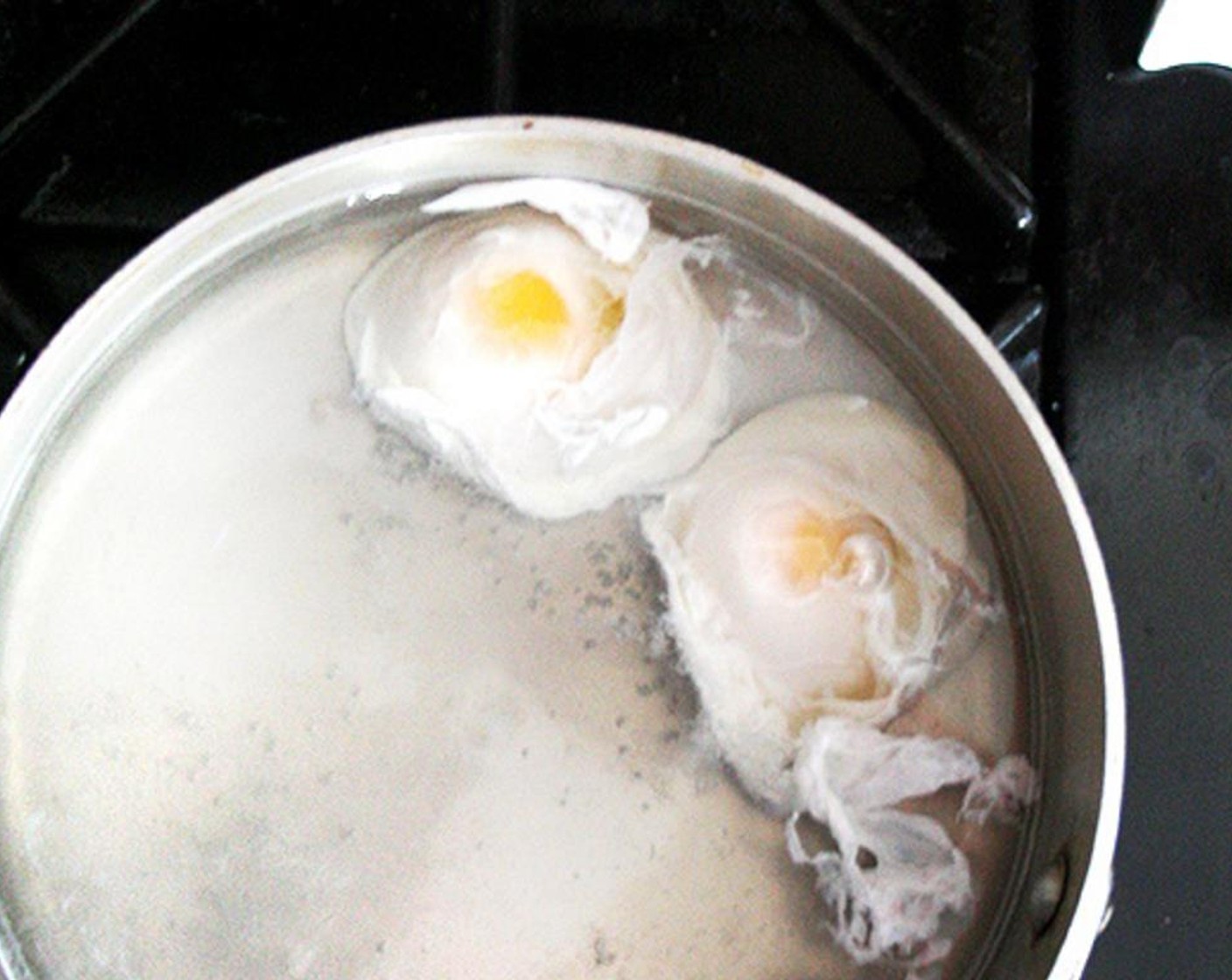step 11 Use the handle of a wooden spoon to make a whirlpool in the water, then drop one egg into the center of the whirlpool. Repeat with the other egg. Adjust the heat to keep the water just below a simmer. Set the timer for 3 minutes.