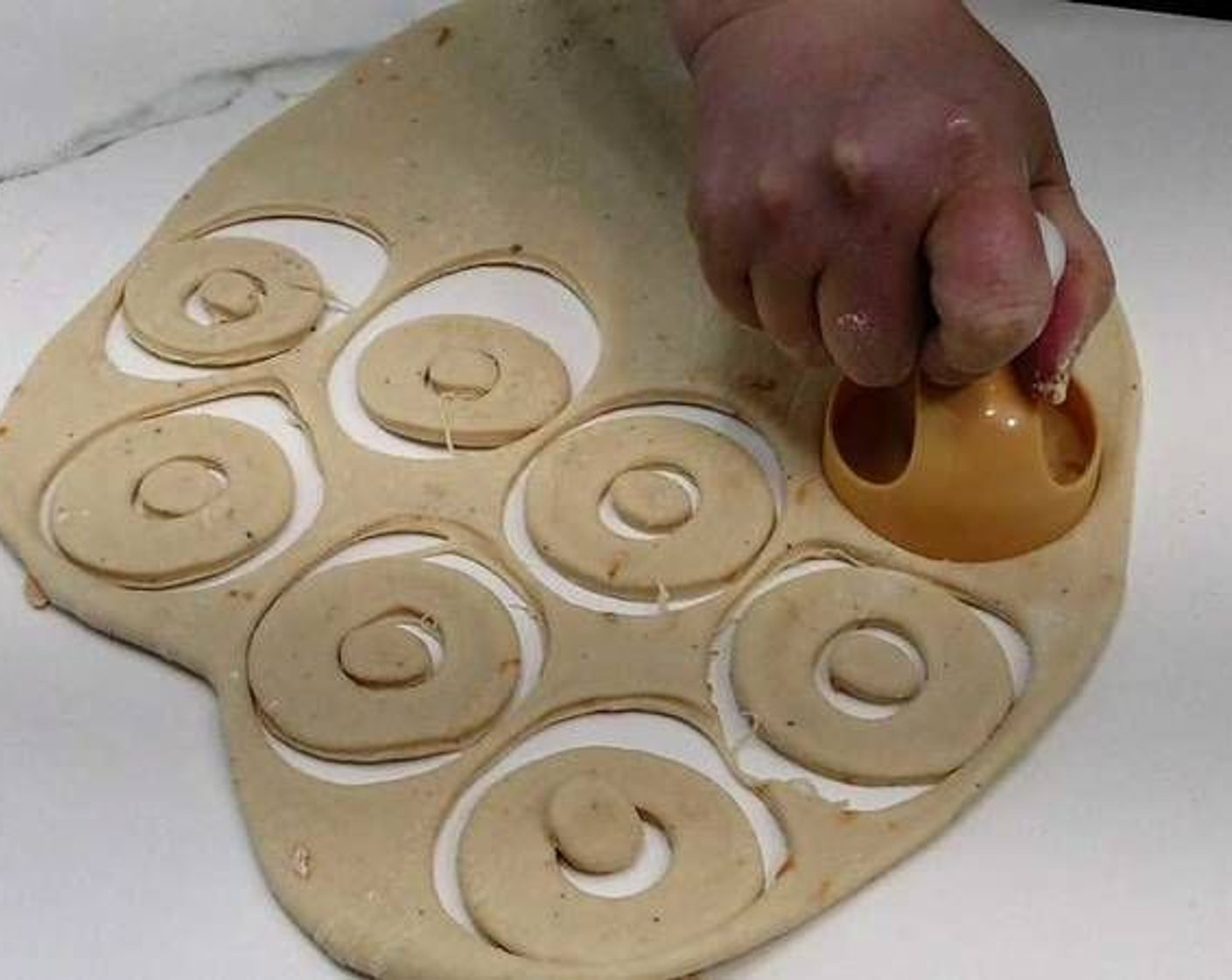 step 7 Sprinkle your working surface with flour again and knead the dough again. Roll out the dough with a rolling pin, cut with a circular cutting tool used for donuts. Place the donuts on a tray lined with baking paper and let rest covered with a cloth for a bit.