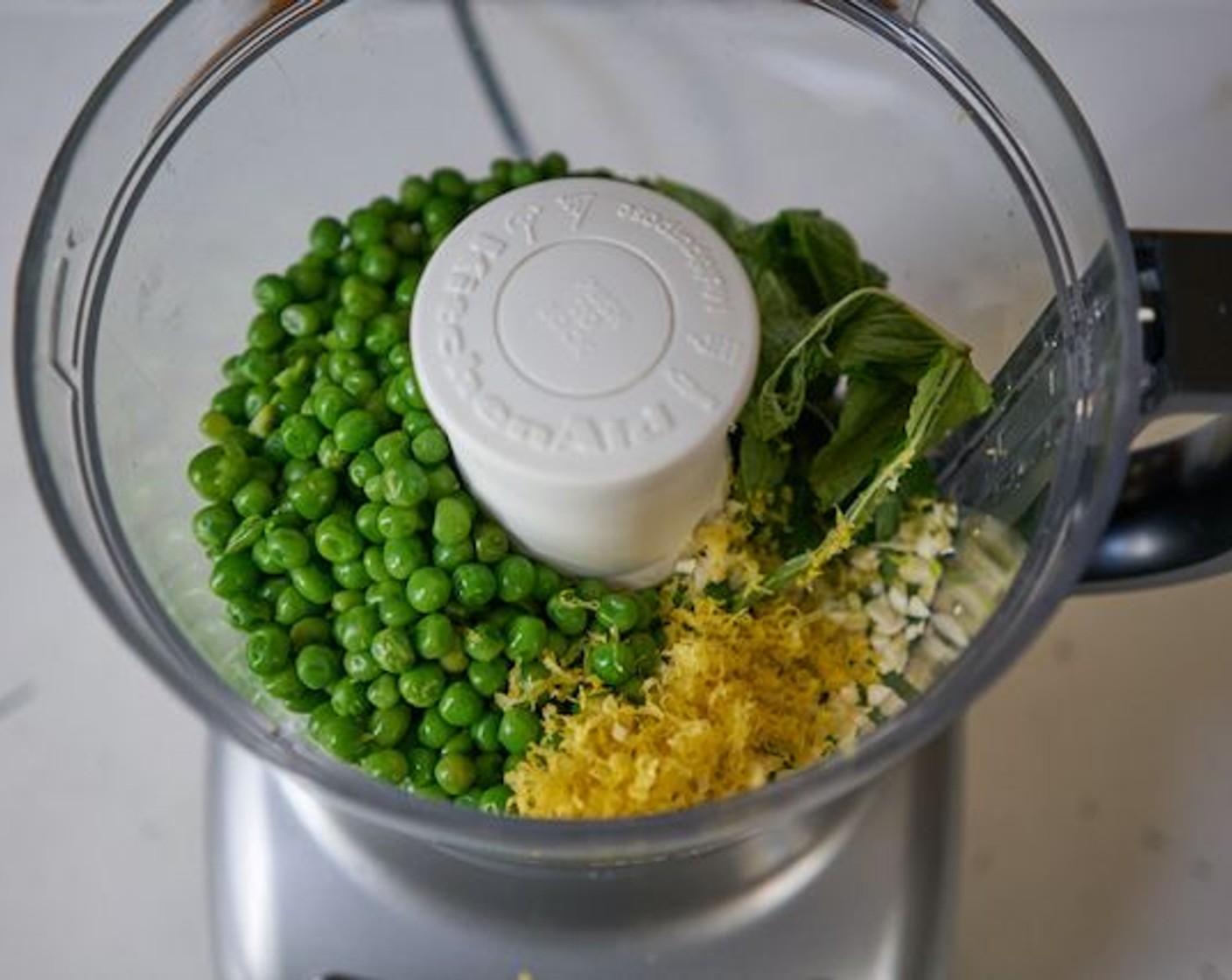step 6 In a food processor, add peas, chopped Garlic (1 clove), zest of the Lemons (3) (reserving about 1/2 tsp for garnish) and 3 Tbsp juice, Fresh Mint Leaves (8), and Olive Oil (4 Tbsp). Season with a pinch of Kosher Salt (to taste) and Freshly Ground Black Pepper (to taste). Pulse until the mixture is coarse. You don’t want pea pureé.