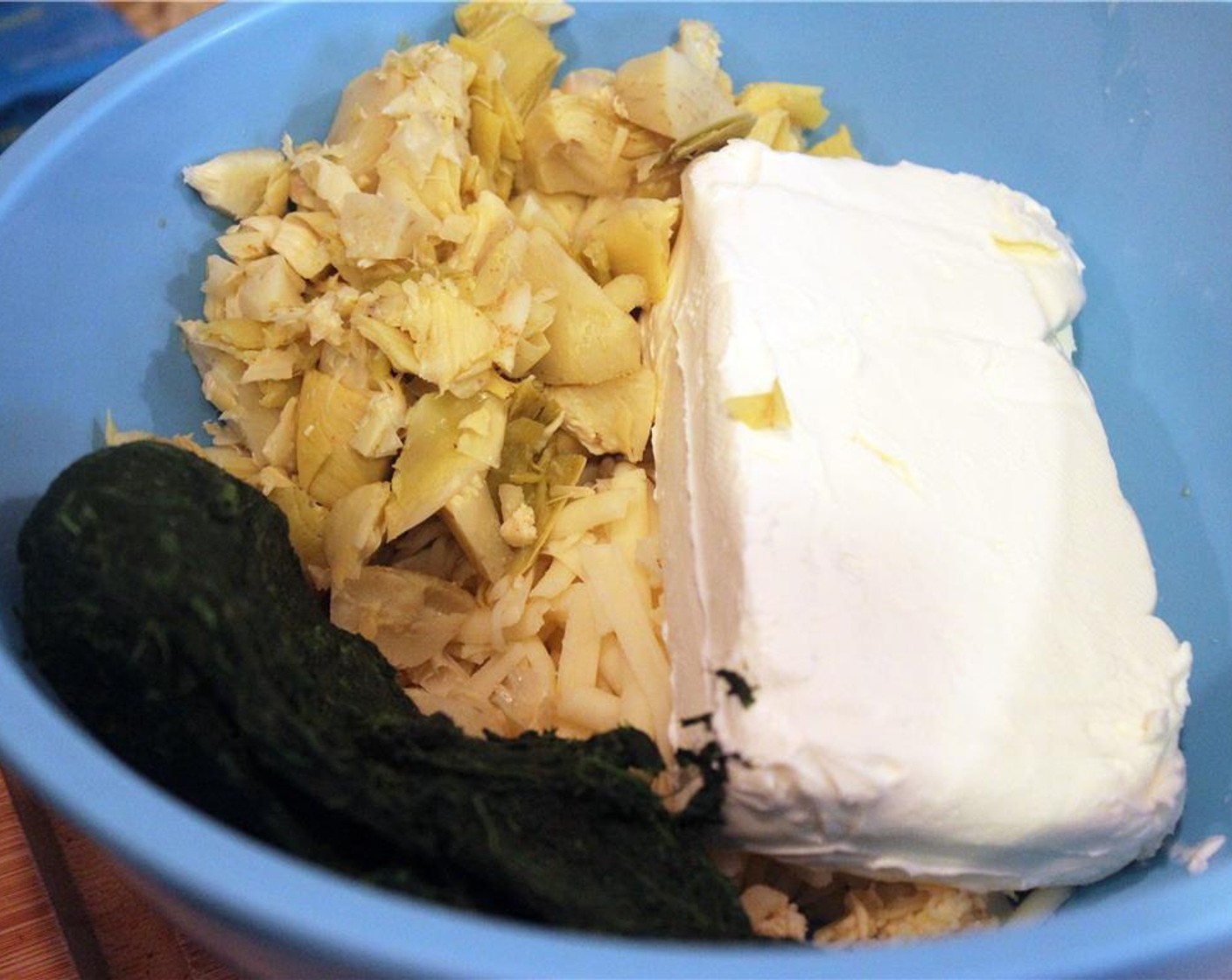 step 7 Add the Cream Cheese (1 pckg), spinach, and chopped artichokes to a bowl and stir to combine.