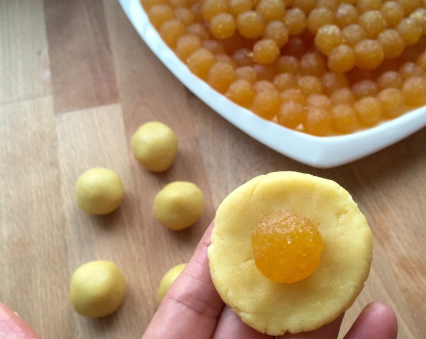 step 14 To make the pineapple tarts, first flatten the rolled dough ball. Then place a piece of the rolled pineapple jam filling in the middle.