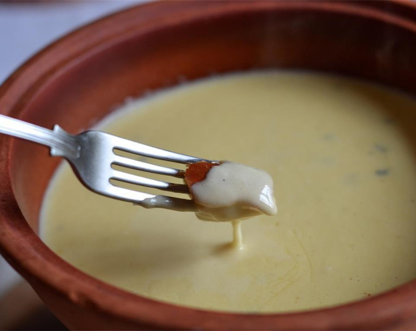 step 4 Meanwhile, rub the inside of a warmed ceramic or earthenware pot with the Halved Garlic (1 clove). When the cheese has melted entirely and the resulting fondue has a creamy silken consistency with a cheesy pull, pour the mixture into the ceramic pot.