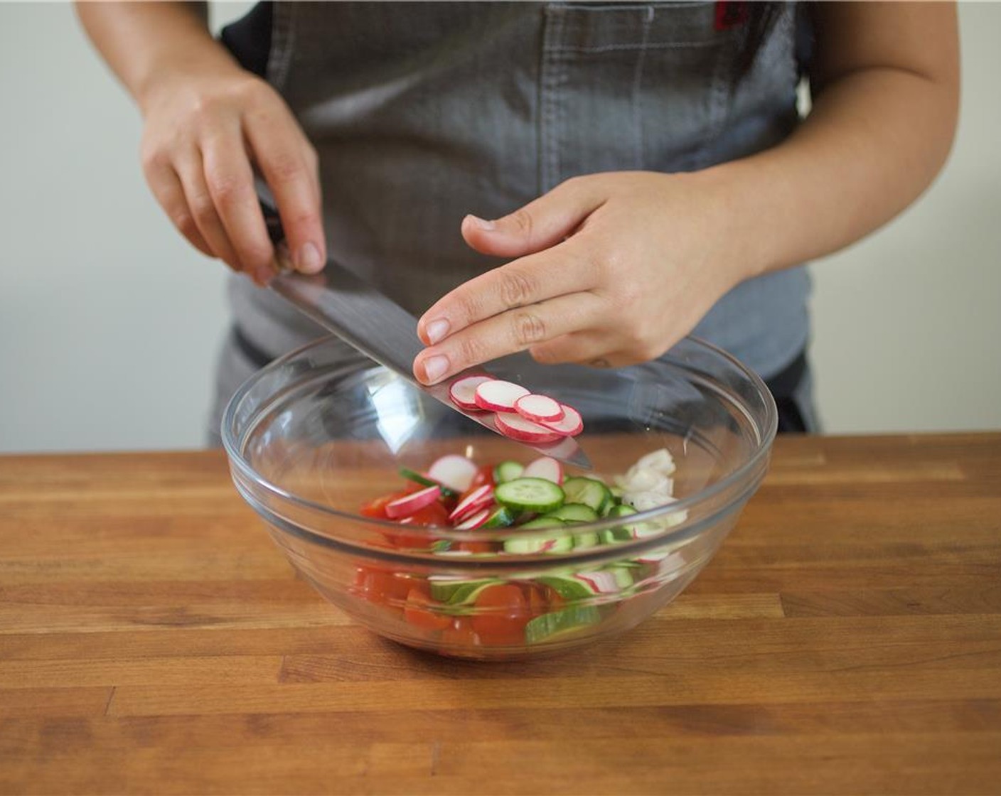 step 6 Meanwhile, rinse and dry the bowl. Slice Shallot (1) in half lengthwise, then slice across; place in a large bowl. Slice Mini Cucumber (1) in half lengthwise, then across in 1/4-inch thick half-moon slices; add to bowl. Slice Radish (1 bunch) into thin circles; add to bowl. Cut the Cherry Tomato (1 cup) in half. Slice Scallion (1 bunch) into 1/4 inch thick slices; hold for next step.