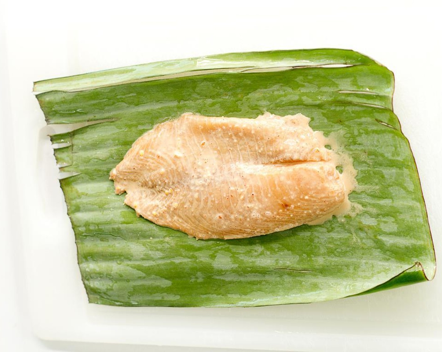 step 7 Place a Banana Leaves (2) seam side up on a cutting board. Take a marinated fish filet and place in the center of the leaf.