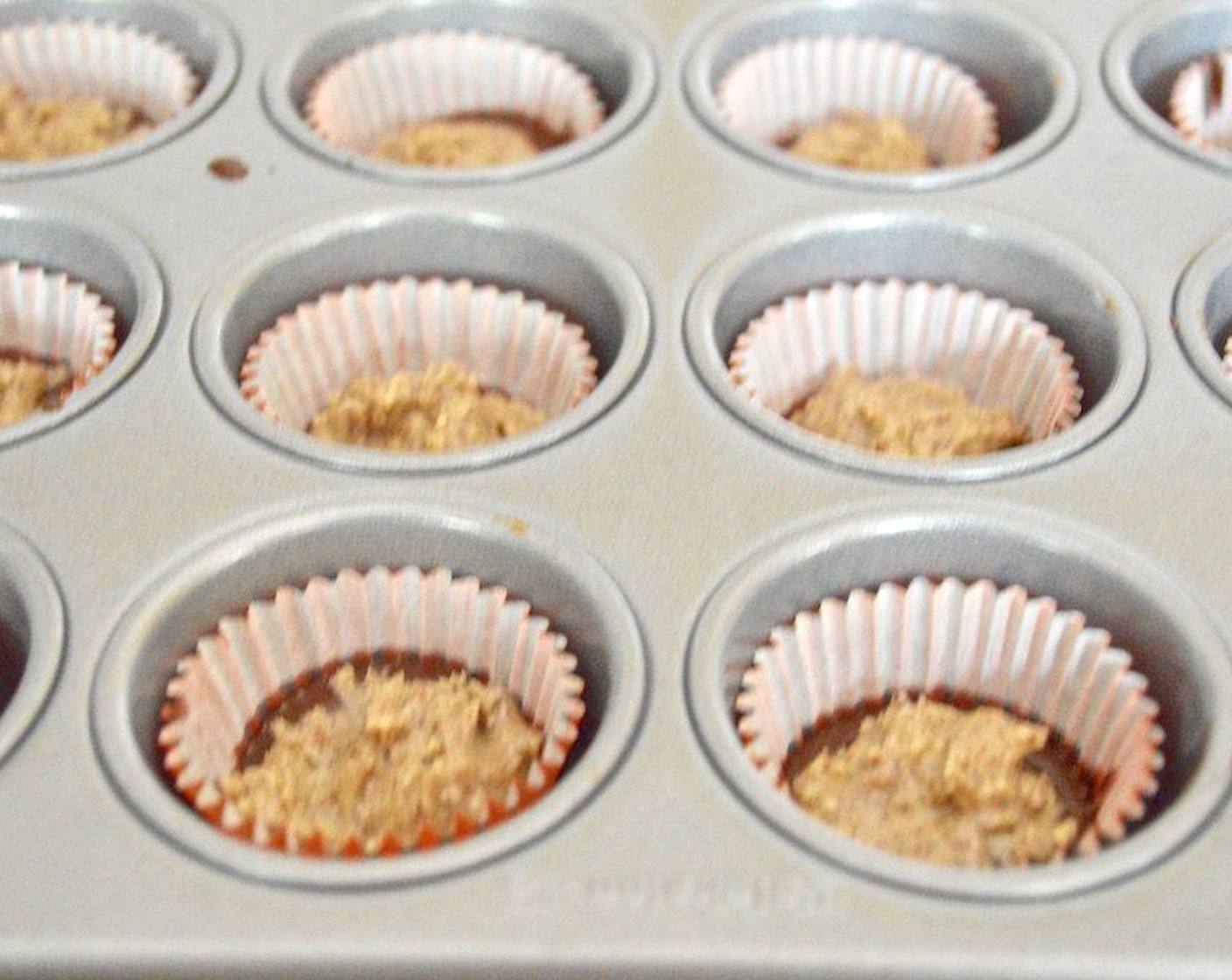 step 4 Take the chocolate mixture and scoop a teaspoon into the bottom of each well to form the base. Nudge it around to make sure it completely gets into the ridges of the liners. Then scoop a heaping 3/4 teaspoon of the almond butter filling on top of each chocolate base.