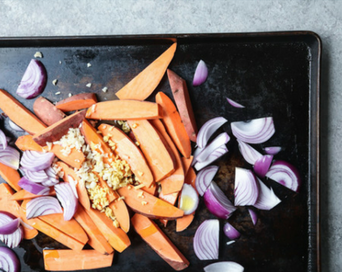 step 2 On a large rimmed baking sheet, toss Sweet Potato (1 lb), Red Onion (1), Garlic (2 cloves) and Fresh Ginger (1 in) with Olive Oil (2 Tbsp) and Sea Salt (1/2 tsp). Arrange in an even layer on the sheet pan.