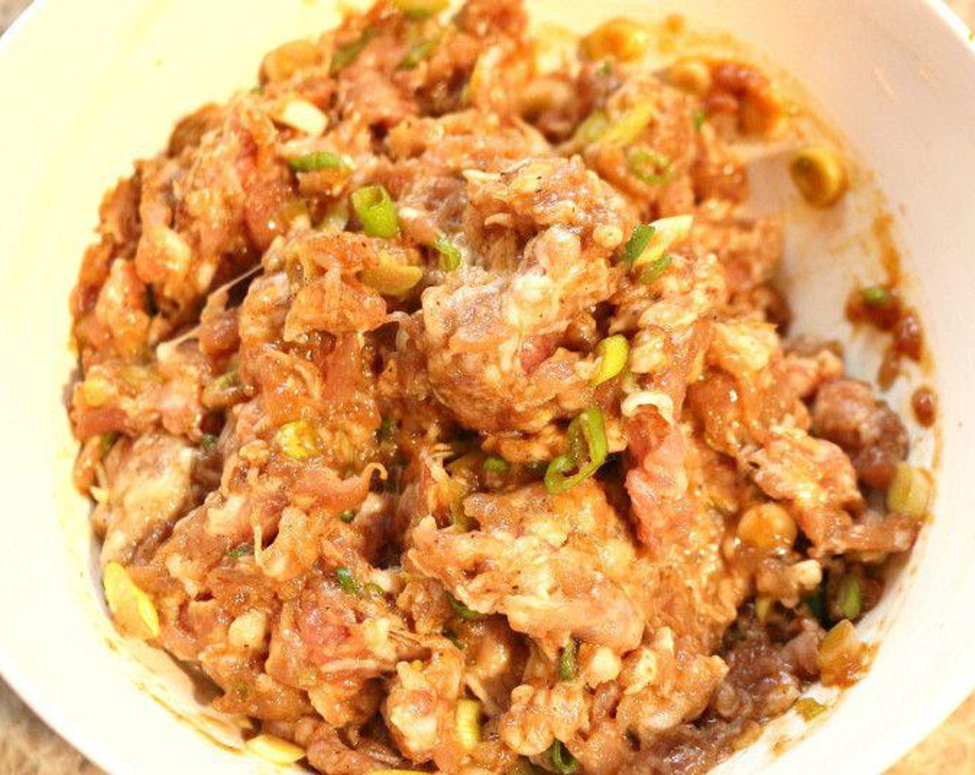step 2 Meanwhile, mix Ground Pork (14 oz) with sliced Scallions (2 stalks), Eggland's Best Classic Egg (1), Chinese Five Spice Powder (to taste), and additional garlic paste, grated ginger, and salt and white pepper.