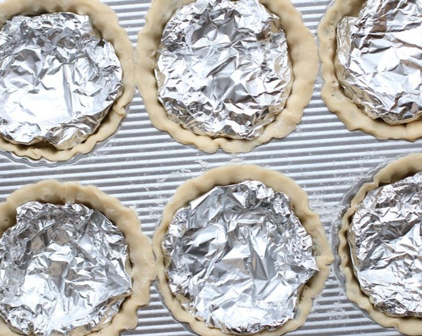 step 7 Cut foil into six 7-inch widths.  Fold and shape foil so that one piece will fit inside each tart shell like this.