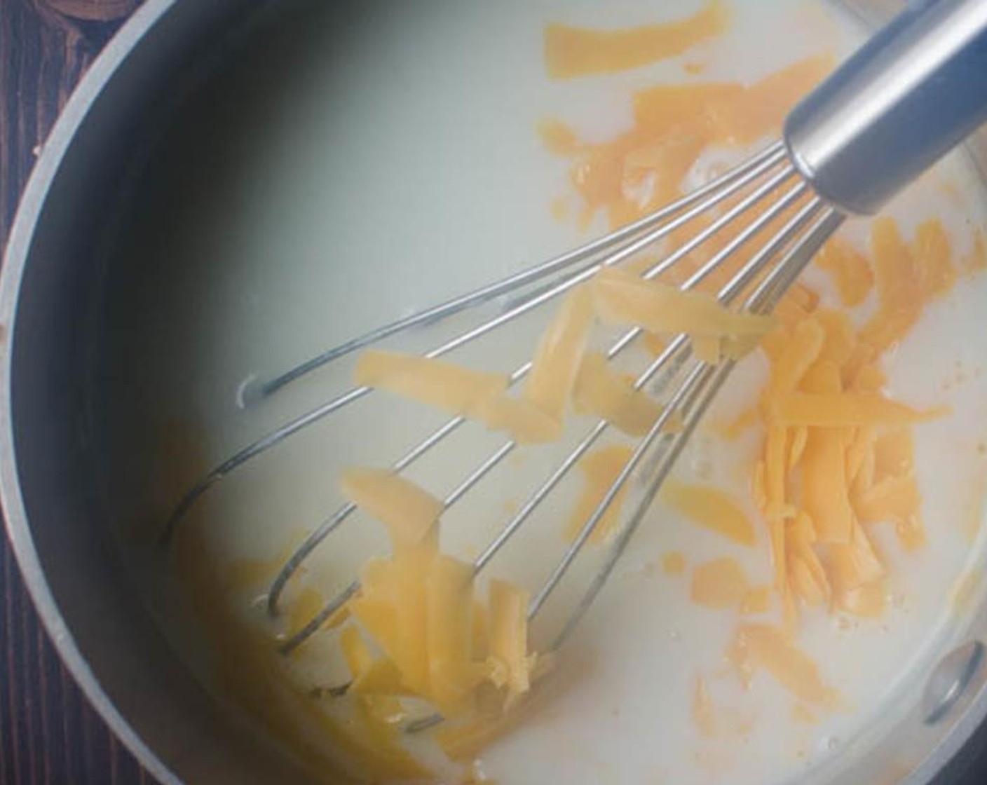 step 8 Gradually whisk in the Milk (3 cups) a little at a time. Bring to a boil over medium high heat and cook for 1 minute until sauce is thickened. Remove from heat and stir in the Cheddar Cheese (1 cup).