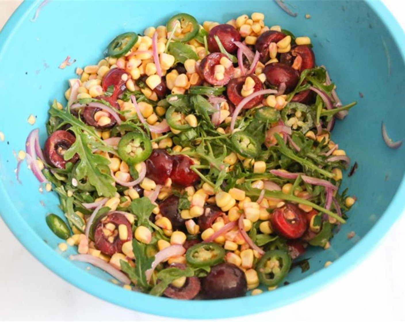 step 4 Carefully slice the kernels from each ear of Sweet Corn (2 ears) into a large mixing bowl. Add the Sweet Cherries (2 cups), very thinly sliced Red Onion (1/4 cup), Jalapeño Pepper (1), Baby Arugula (1 cup) and Fresh Basil Leaves (8) to the bowl and toss to combine.