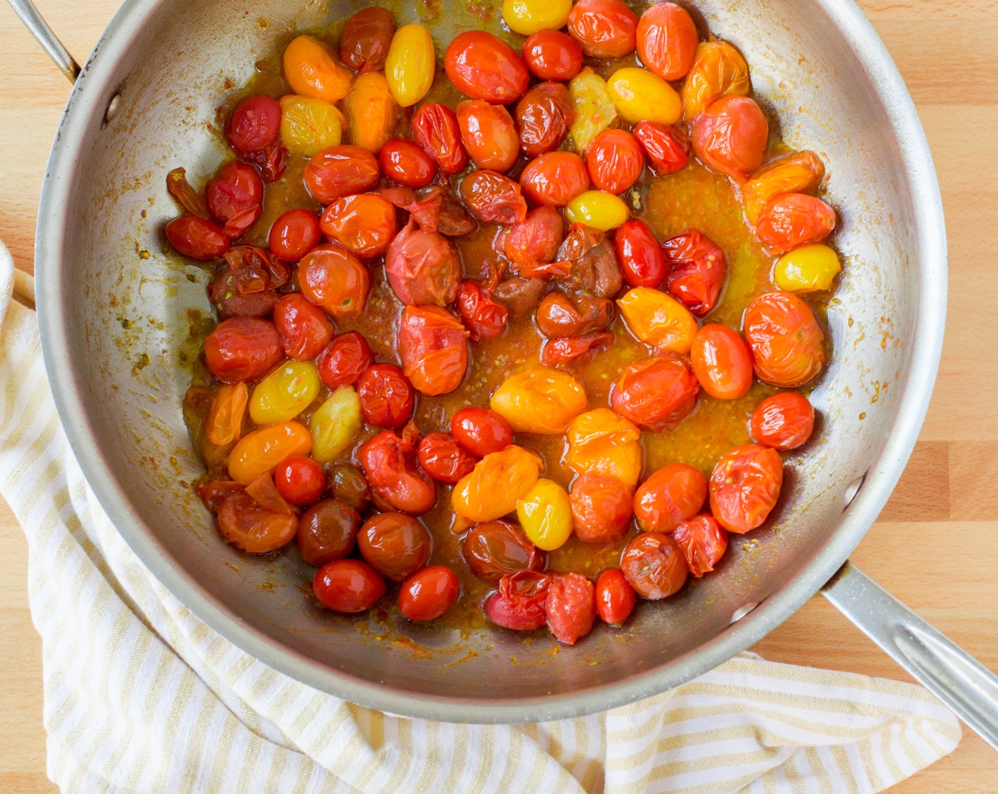 step 2 While the pasta is cooking, make the sauce. Heat the Extra-Virgin Olive Oil (3 Tbsp) over medium-high heat in a large, heavy-bottomed skillet or sauté pan. Add the Cherry Tomatoes (4 1/2 cups) and sauté until they are soft and begin to break down; 4 to 5 minutes. Gently press on the tomatoes with the back of a wooden spoon to release their juices.