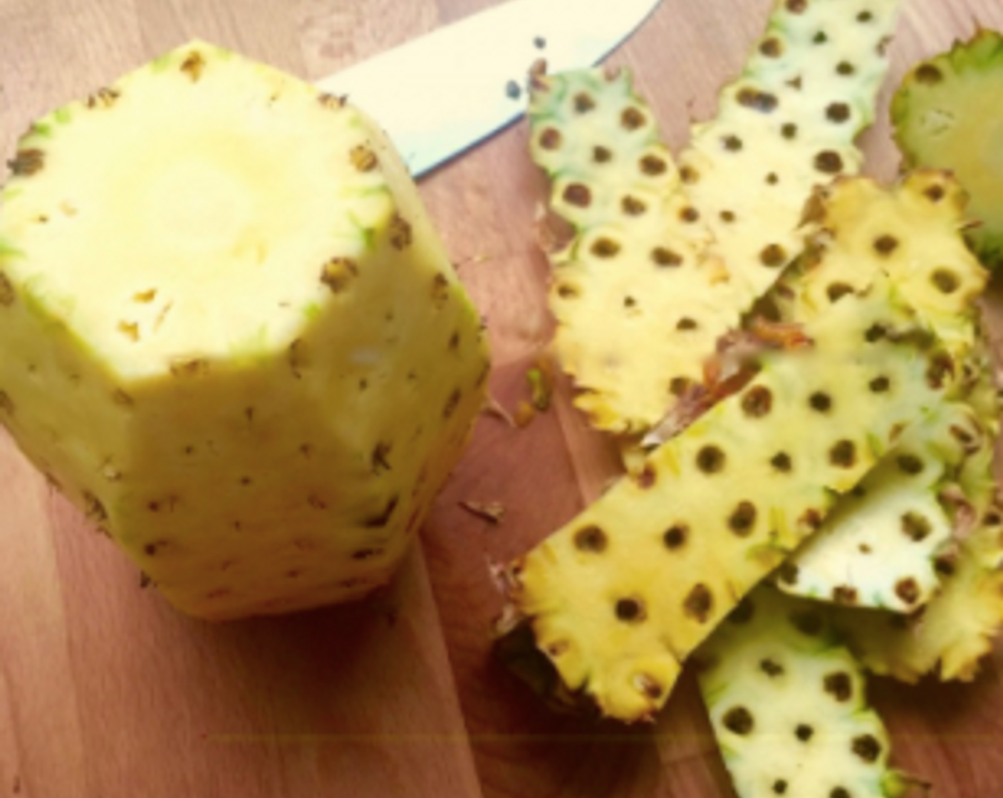 step 5 Next, stand the pineapple upright and with a sharp knife, cut away the outer tough skin in strips, from top to bottom.