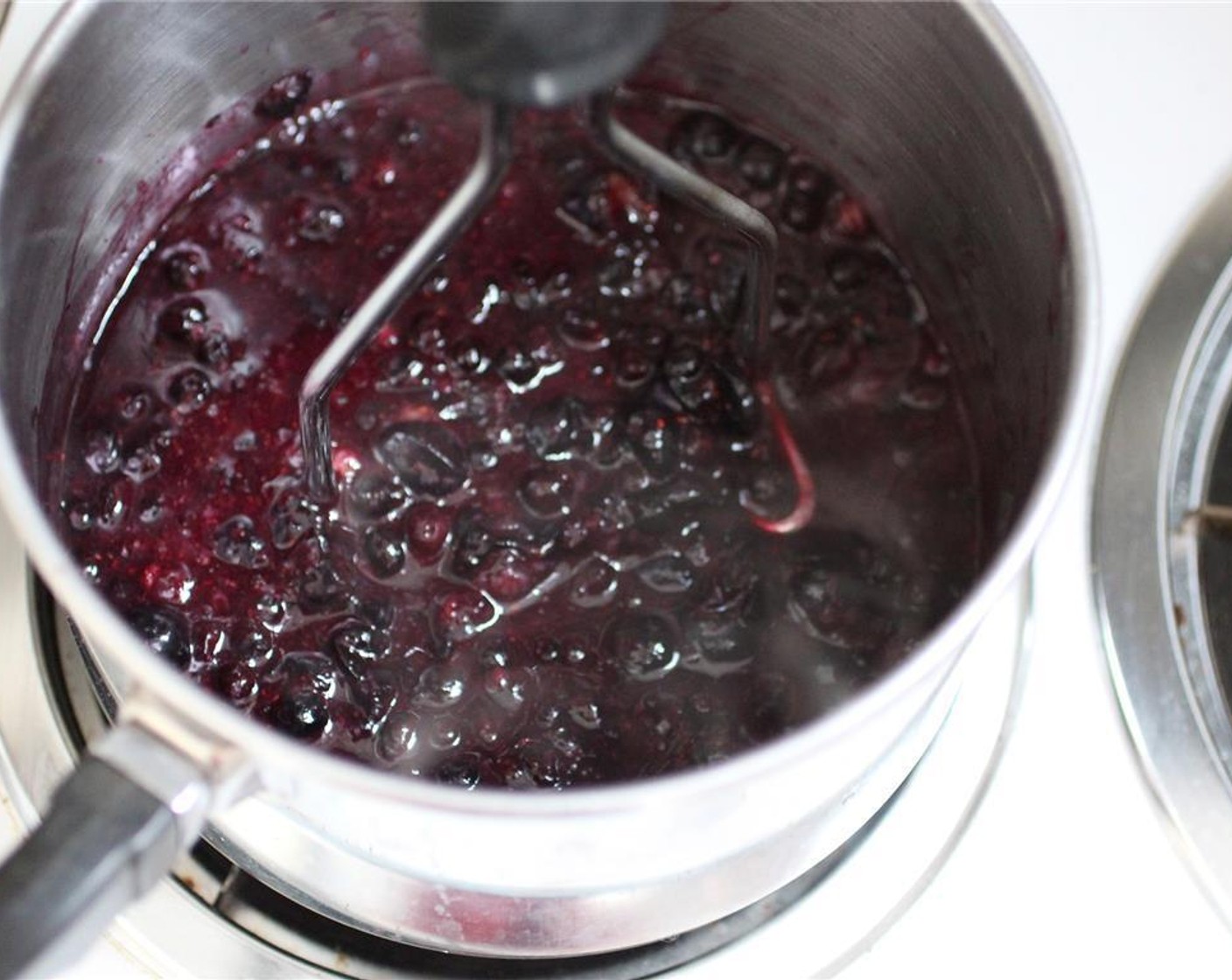 step 2 As the blueberries soften, use a spatula and potato masher to break down the berries as much as you like.