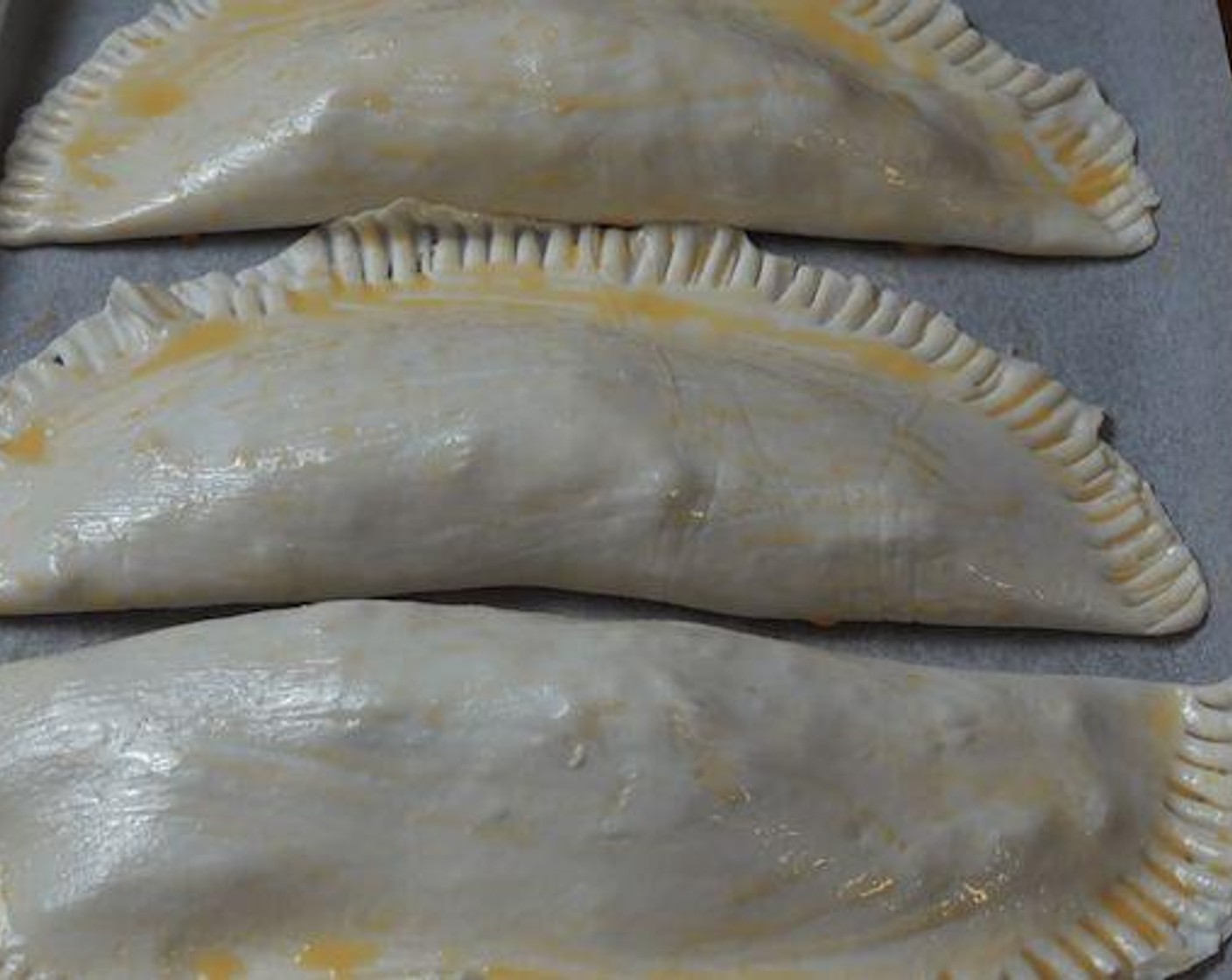 step 6 Fold the pastry over and using a fork crimp the edges together to seal the pies. Transfer the pies onto a baking tray lined with non-stick baking paper. Brush each pie with the remaining egg wash.