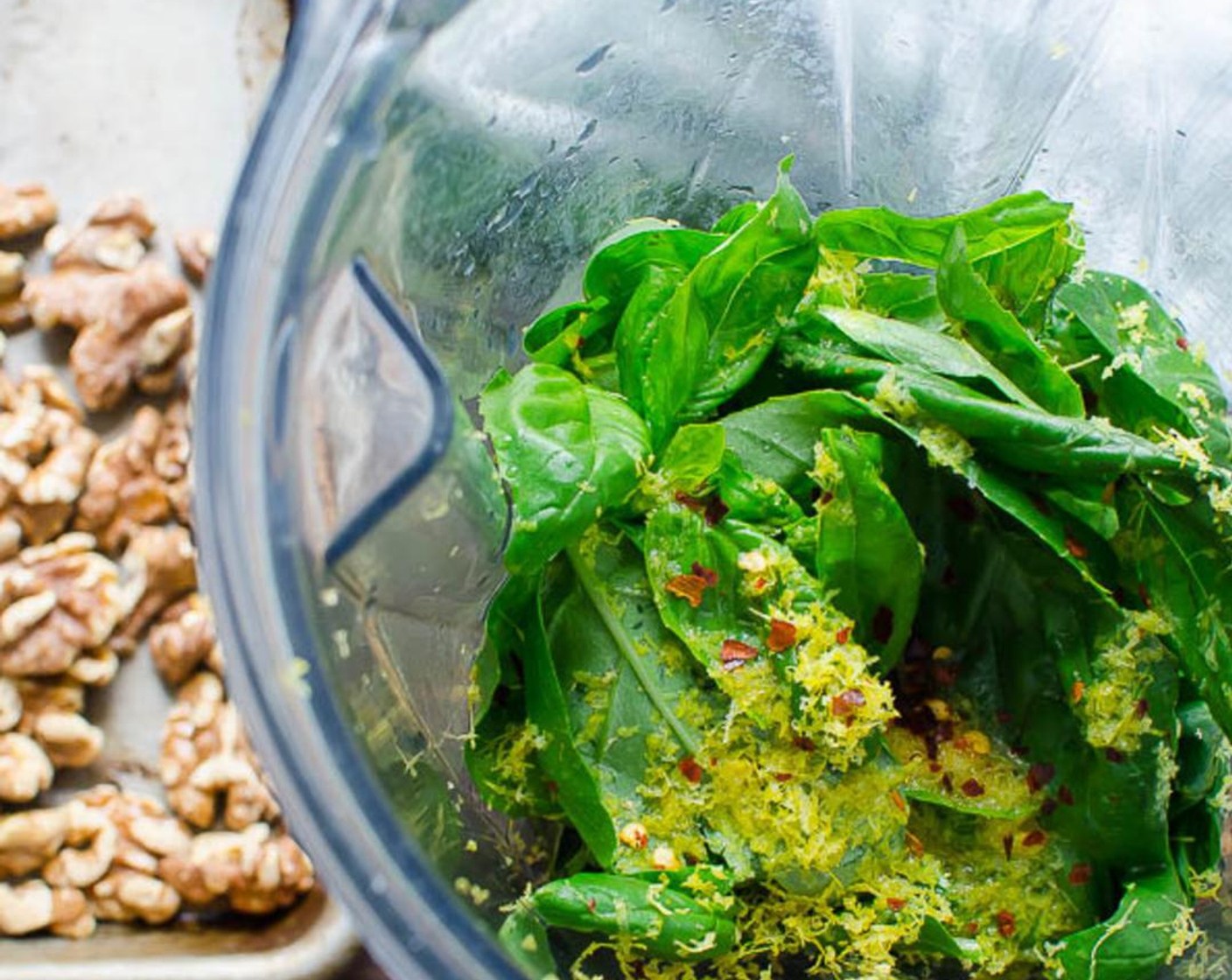 step 1 To the bowl of a food processor or Vitamix blender, add Fresh Basil Leaves (4 cups), toasted Walnut (1/2 cup), Garlic (3 cloves), Crushed Red Pepper Flakes (1/4 tsp), Parmigiano-Reggiano (1/2 cup), Lemon (1).