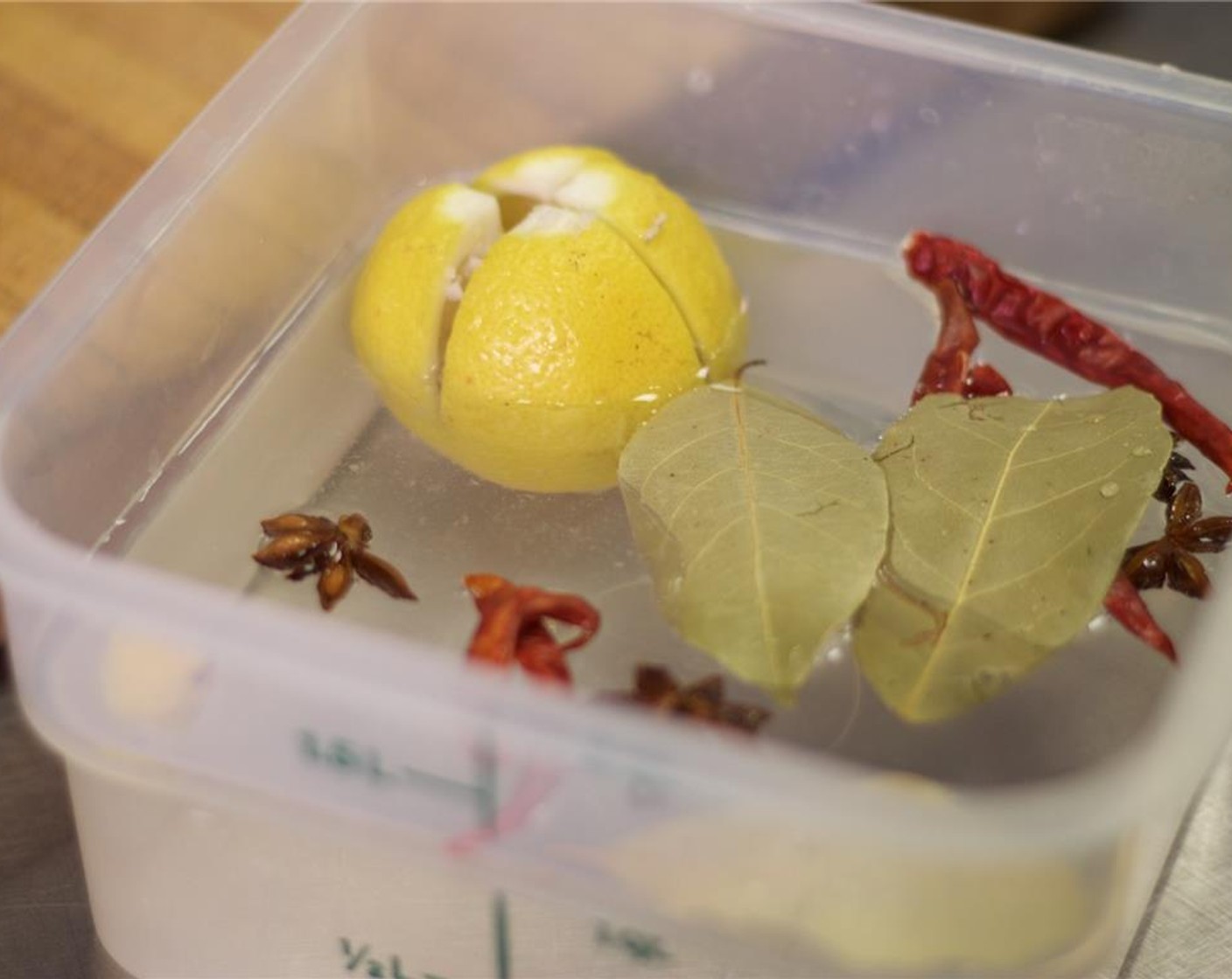 step 3 Place the lemon in a container with the bay leaves, star anise, dried chili, and Granulated Sugar (1 Tbsp).