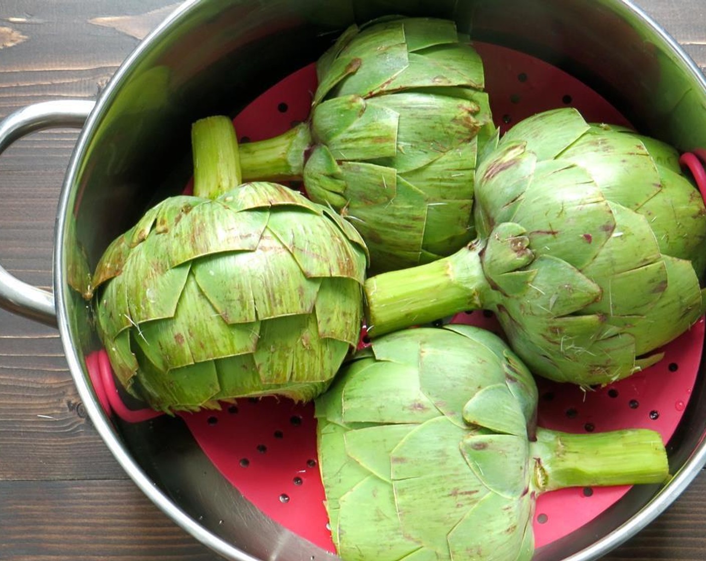 step 6 When the water is boiling, place the artichokes, cut side down onto the steaming tray and steam them for 25-40 minutes, depending on your artichoke. Check doneness by how easily one of the petals can be pulled from the bottom of the vegetable.