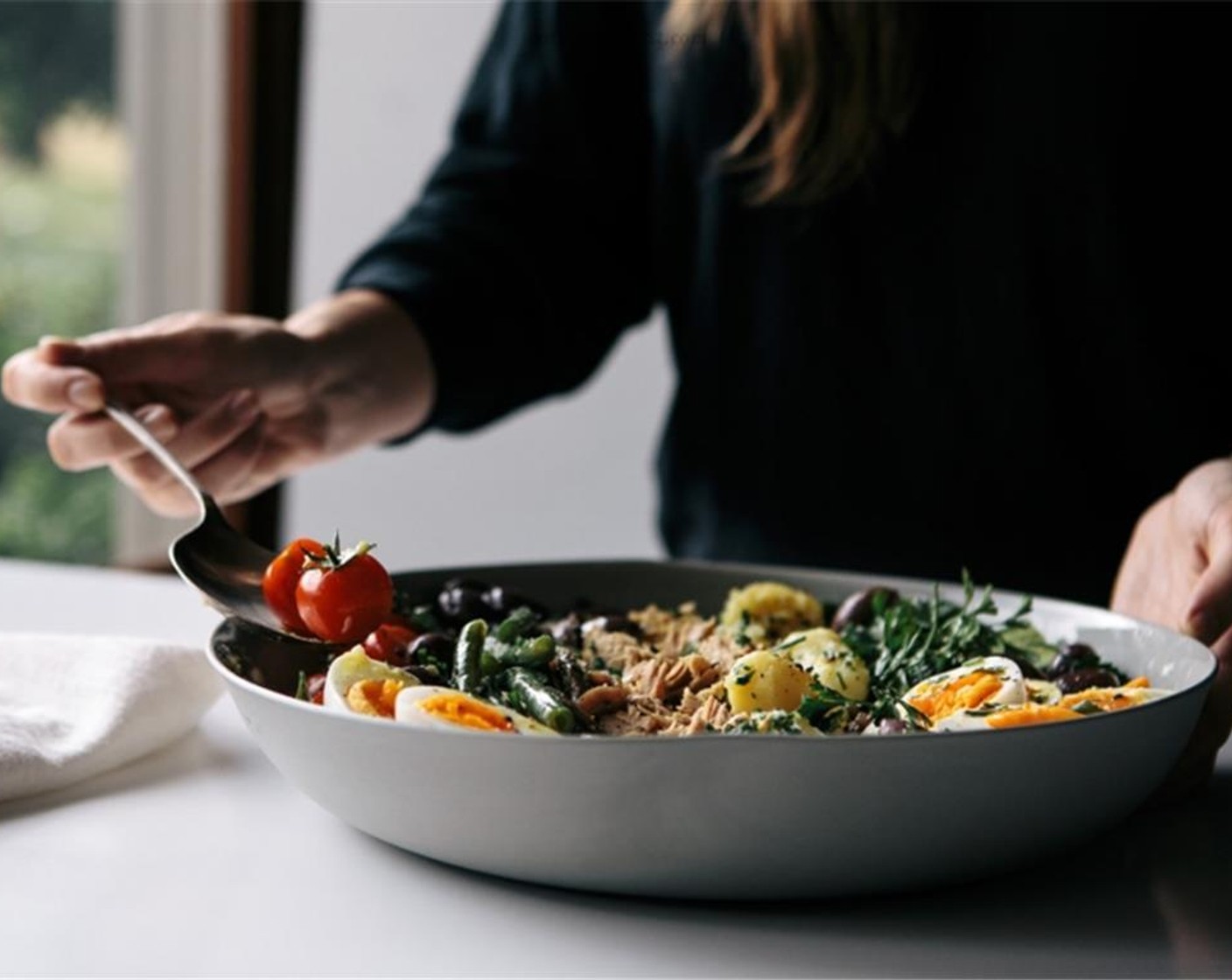 step 6 Place the cooked potatoes, Truss Tomatoes (10), Lebanese Cucumber (1), cooked green beans and Kalamata Olives (1/2 cup) into a serving bowl, then add the drained Canned Tuna (1 can), Anchovies (8), and eggs on top.