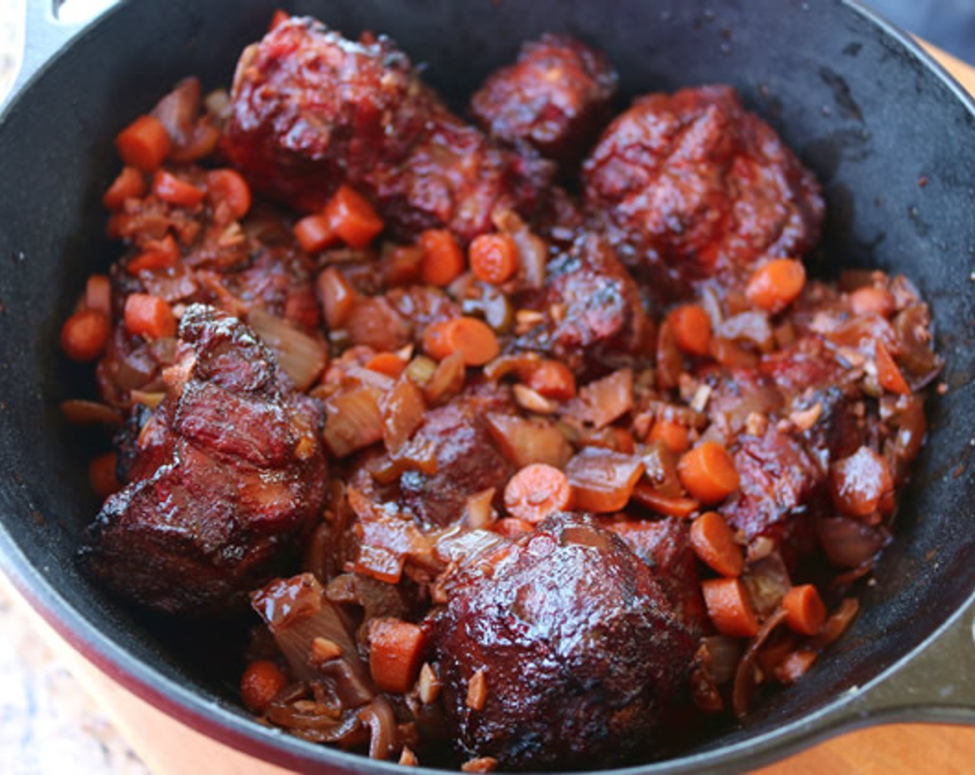 step 8 Remove oxtails from smoker and arrange in a large cast iron pot. Pour braising sauce around meat and cover with aluminum foil.