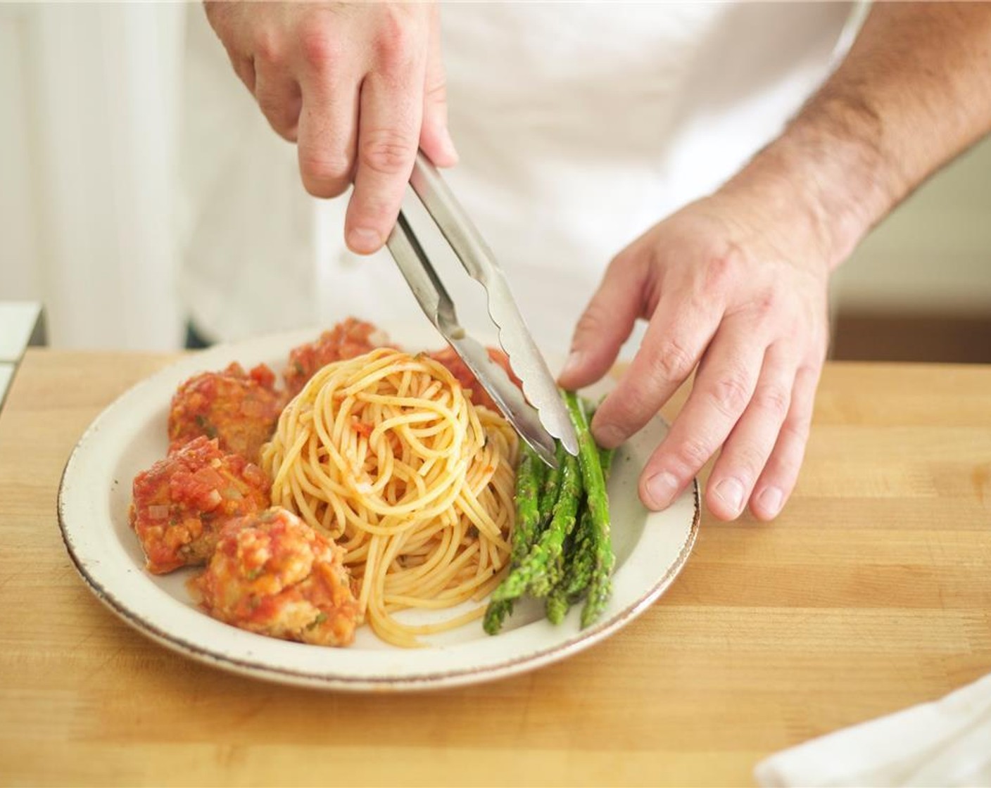 step 24 Divide the pasta between two plates. Place meatballs over the pasta with an even amount of sauce on both dishes. Sprinkle with the remaining Parmesan Cheese (4 Tbsp). Place the asparagus on the side.