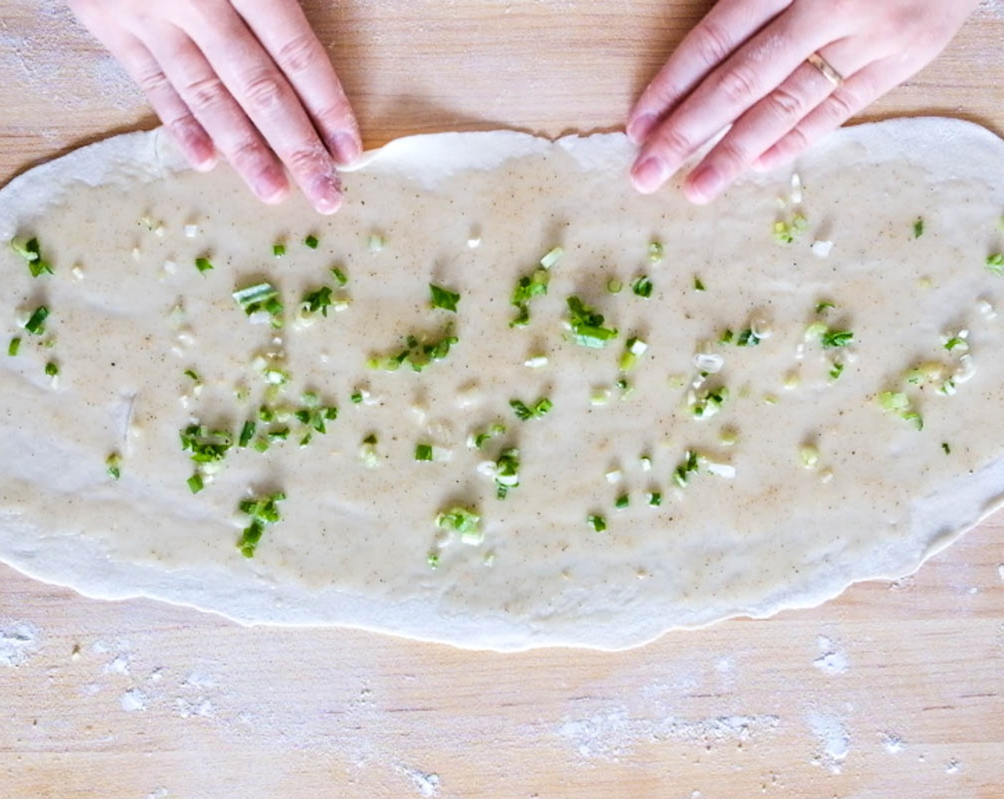 step 7 Use a flat rolling pin to roll the ball out into a strip, as thin as you can without tearing the dough, about 45cm (18-inch) long. Smear one-sixth of the paste on top of the strip and sprinkle one-sixth of the green onions all the way down the strip.