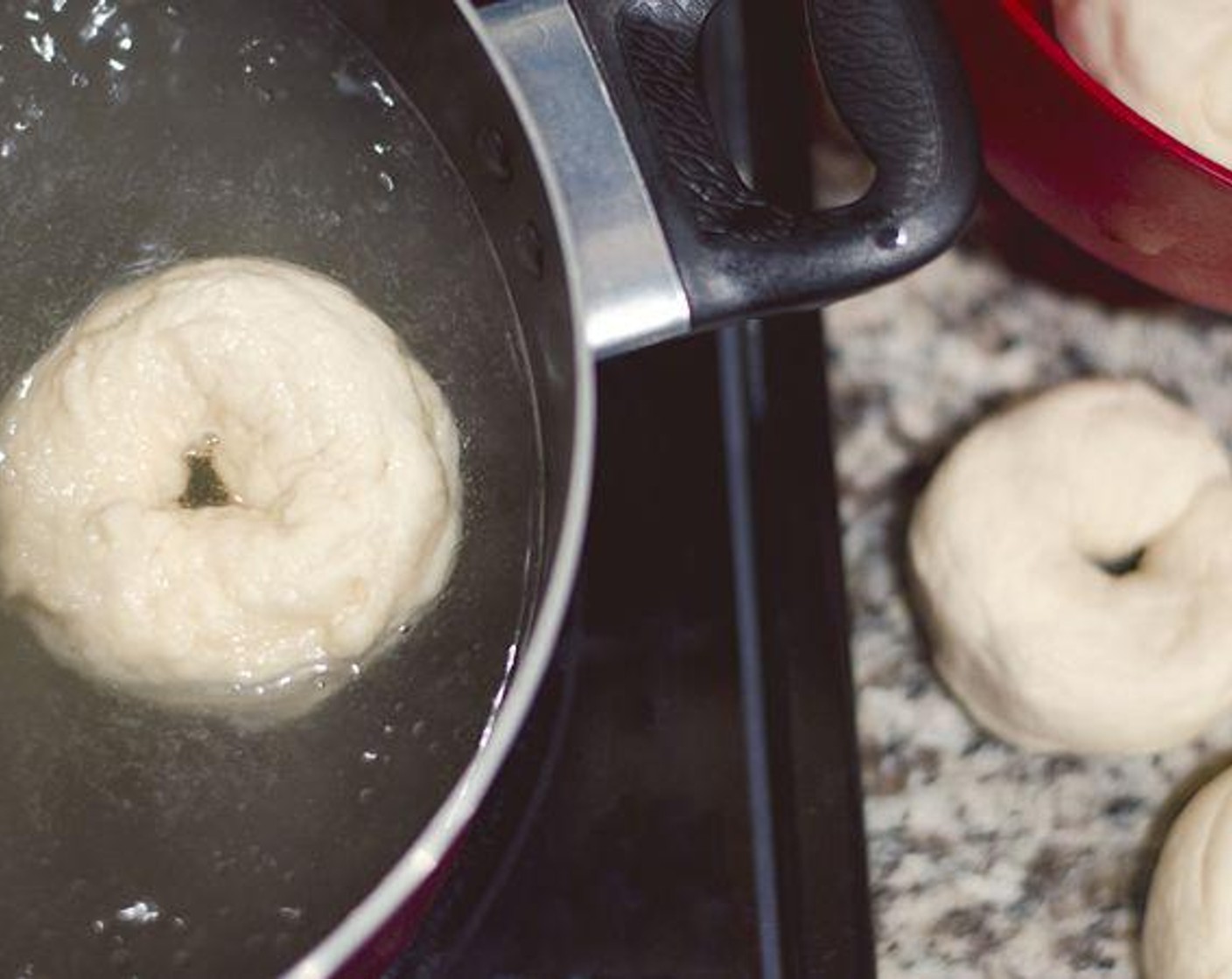 step 5 With a slotted spoon, lower each bagel into boiling water and let cook 30-60 seconds on each side. Do not overcrowd pot. Boil about 4 bagels at a time. Remove with slotted spoon as finished and place on greased cookie sheet.