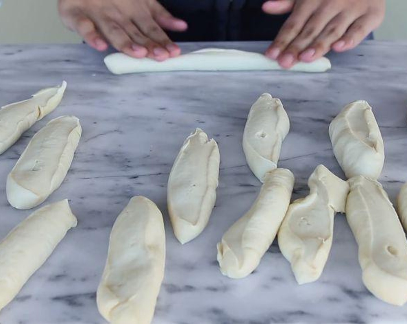 step 4 After time passes, remove dough from the bowl, place it on your work surface and form it into a 16-inch or so log and divide the dough into 12-14 portions. Roll each piece of dough into a 7-inch log. Place dough log on a baking sheet line with parchment paper, cover and let it rise for 30-45 minutes.