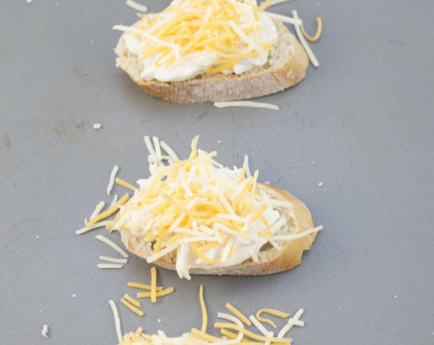 step 5 Top each slice of Baguette (1) with the crab mixture and some Shredded Cheddar Cheese (1/2 cup). Place on an ungreased baking sheet and bake in the preheated oven for 5 minutes until the cheese is melted and golden brown.