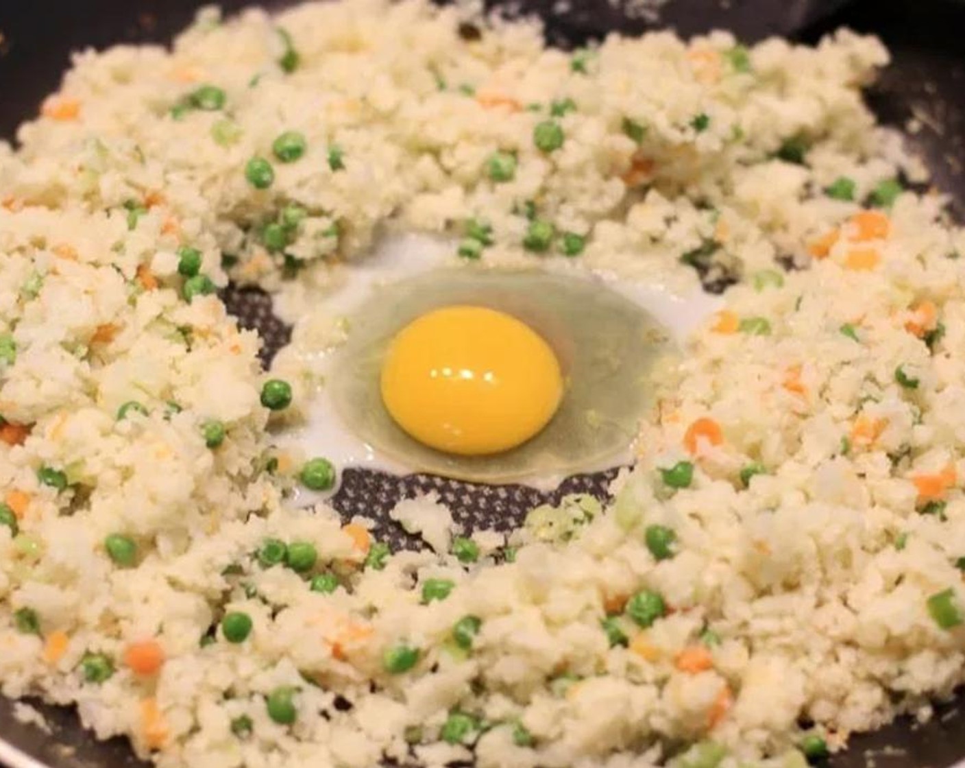 step 5 Create a well in the center of the cauliflower rice and add 1 tsp sesame oil. Crack an Egg (1) in the center and scramble. Once cooked, mix the egg in with the cauliflower rice. Add Salt (to taste), Ground Black Pepper (to taste), and Soy Sauce (3 Tbsp).
