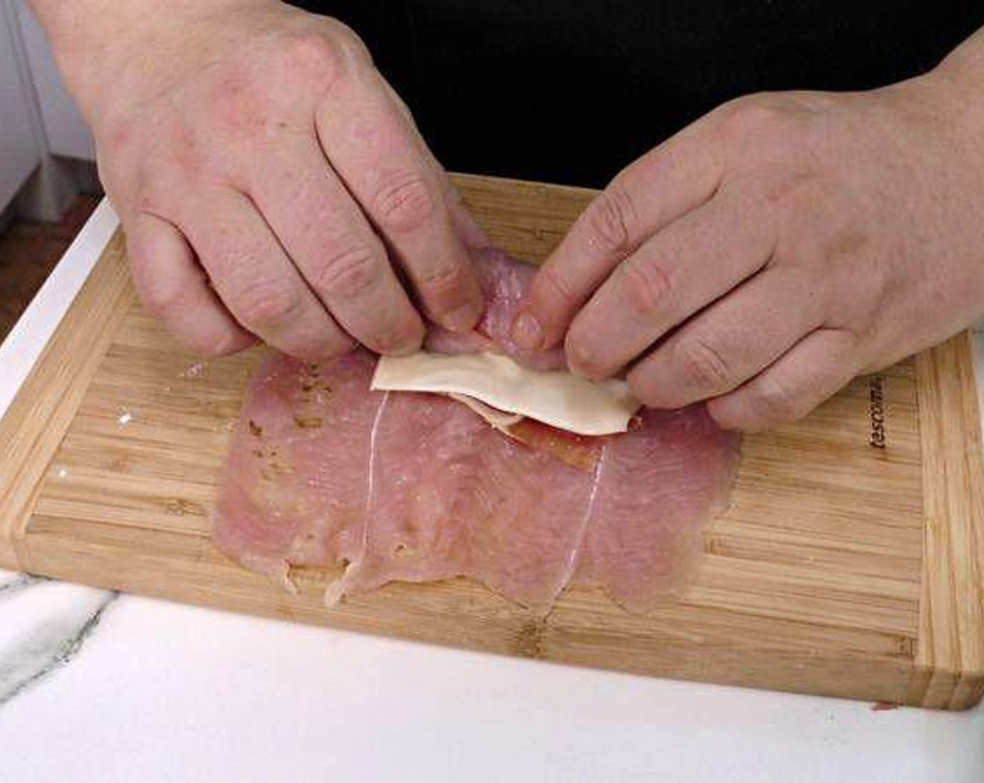 step 2 Next we place the a slice of Serrano Ham (6 slices) and Cheese (6 slices) on top of the chicken fillet so that it covers the fillet and is towards the edge nearest you. Season with Salt (to taste). Roll and hold together by sticking a skewer through. Repeat with remaining ingredients.