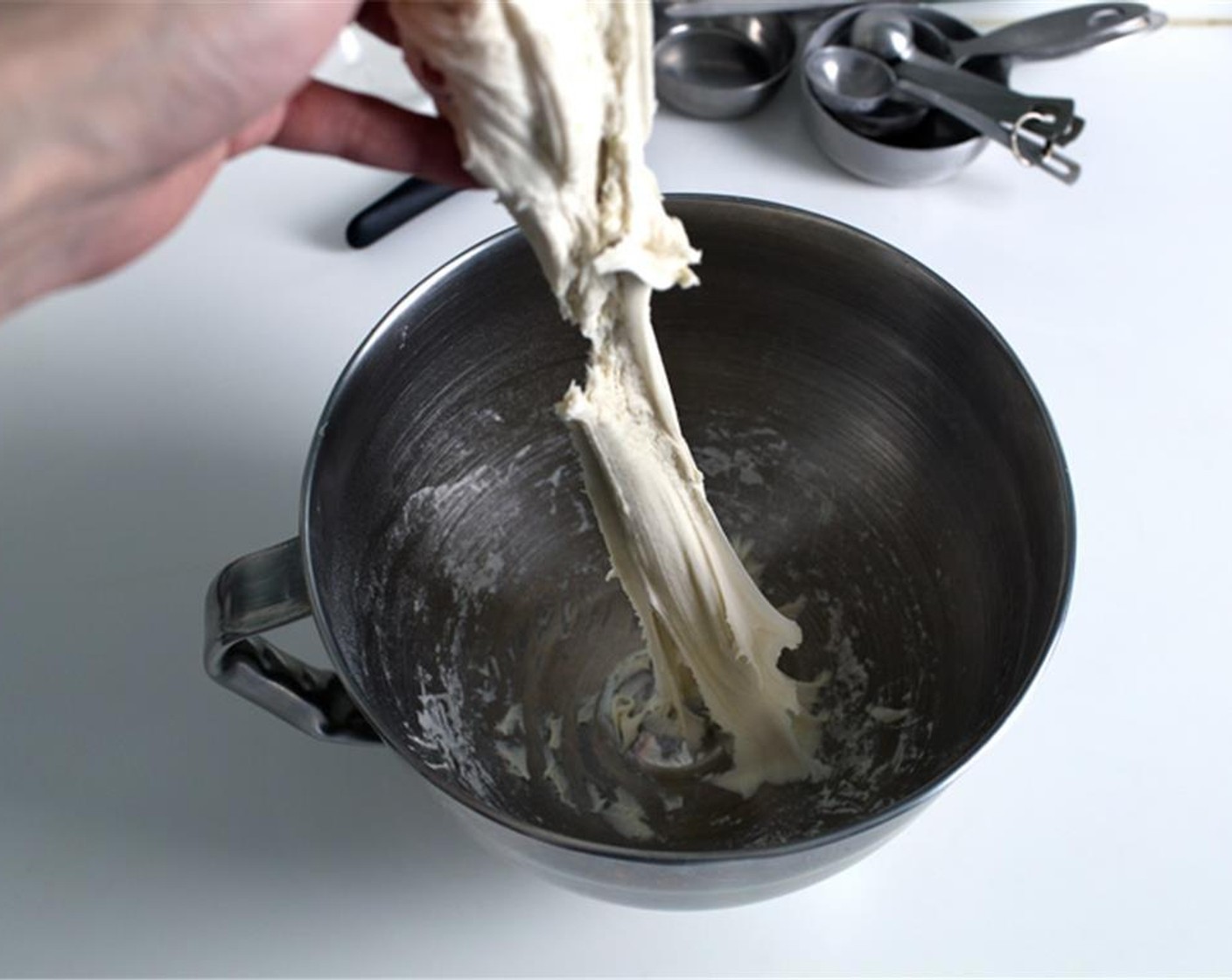 step 12 It will be sticky but pulls away cleanly from the bowl during mixing.  You should be able to “tap” the dough quickly with your finger without it sticking, and pull it slowly upward into 12″ (30 cm) long without breaking. If the dough breaks, either it’s not kneaded sufficiently or it’s too dry. Try kneading it for another 3 minutes first, before adding more water to get the correct consistency.