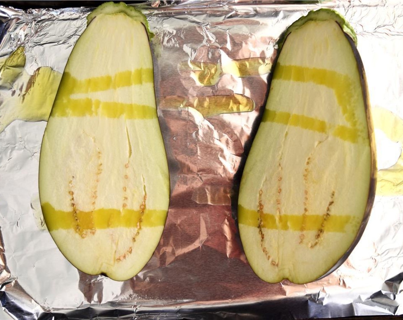 step 1 Preheat oven to 400 degrees F (200 degrees C). Halve the Eggplants (2), rub with Olive Oil (2 Tbsp) and place face down on sheet pan. Bake for 15 minutes or until eggplant is fully cooked. Set aside and let cool.