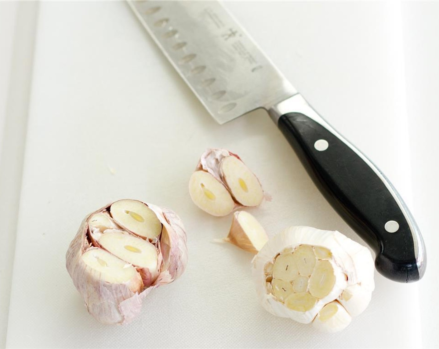 step 2 Leaving the papery skin on the Garlic (1 bulb) take the garlic head and cut about 1/4 – 1/2 inch off the top, exposing the fleshy part of the garlic.