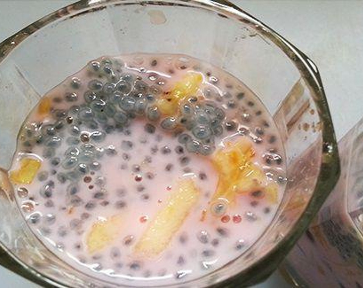 step 4 Now assembling the falooda. There is no specific order for adding the elements, but i always go by this order. To a tall glass pour some Caramel Syrup (to taste). Now add one scoop of the Ice Cream (4 scoops) I am using pista ice cream. Next add soaked basil seeds. Next we will add cooked vermicelli. Next comes chopped fruits. Now pour Milk (1 cup) and again add soaked basil seeds.